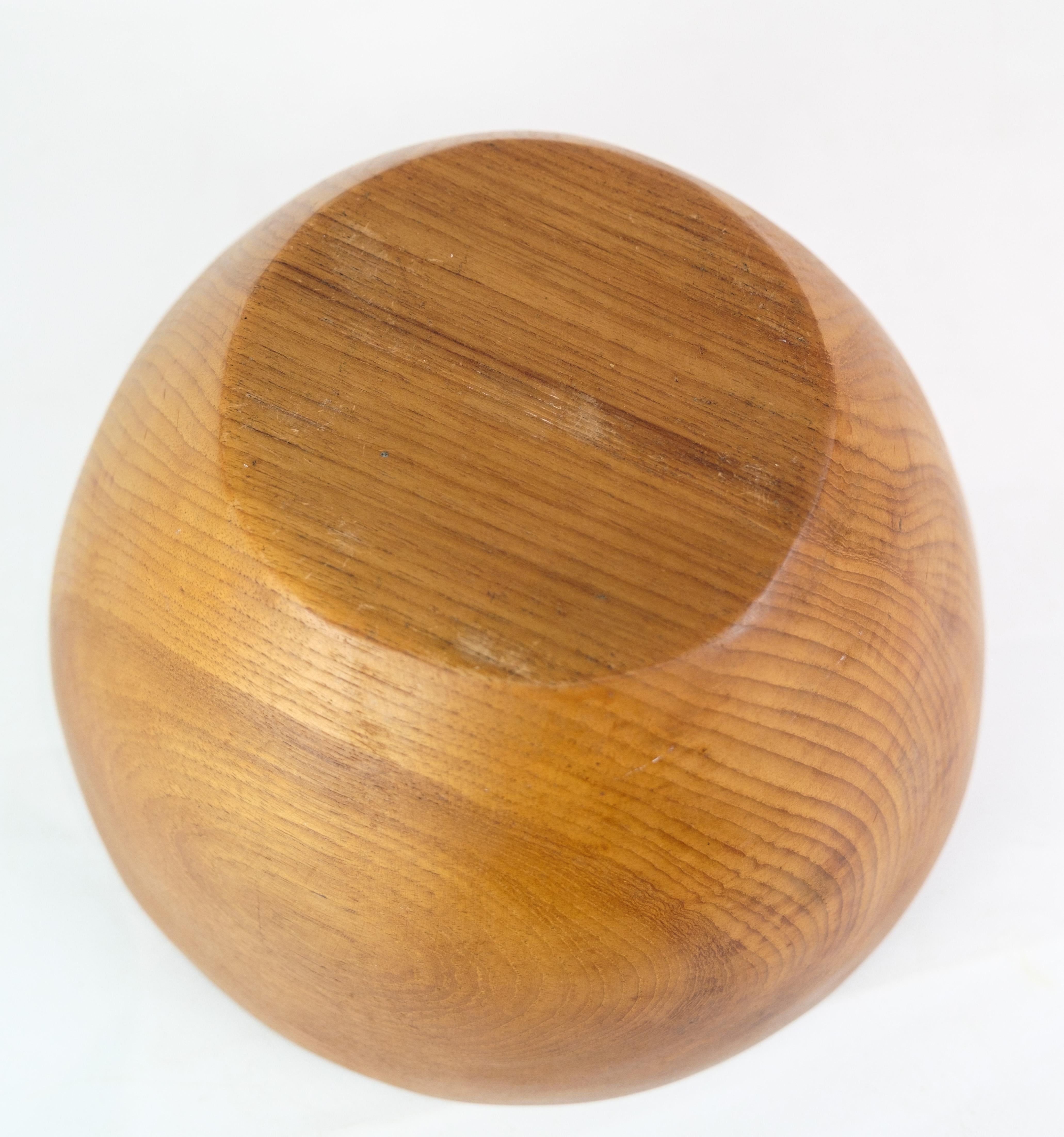 The large teak bowl, crafted in Denmark during the 1960s, exemplifies the era's renowned Danish design principles. This piece showcases the mastery of form and function, with its smooth curves and warm wood grain adding a touch of natural elegance