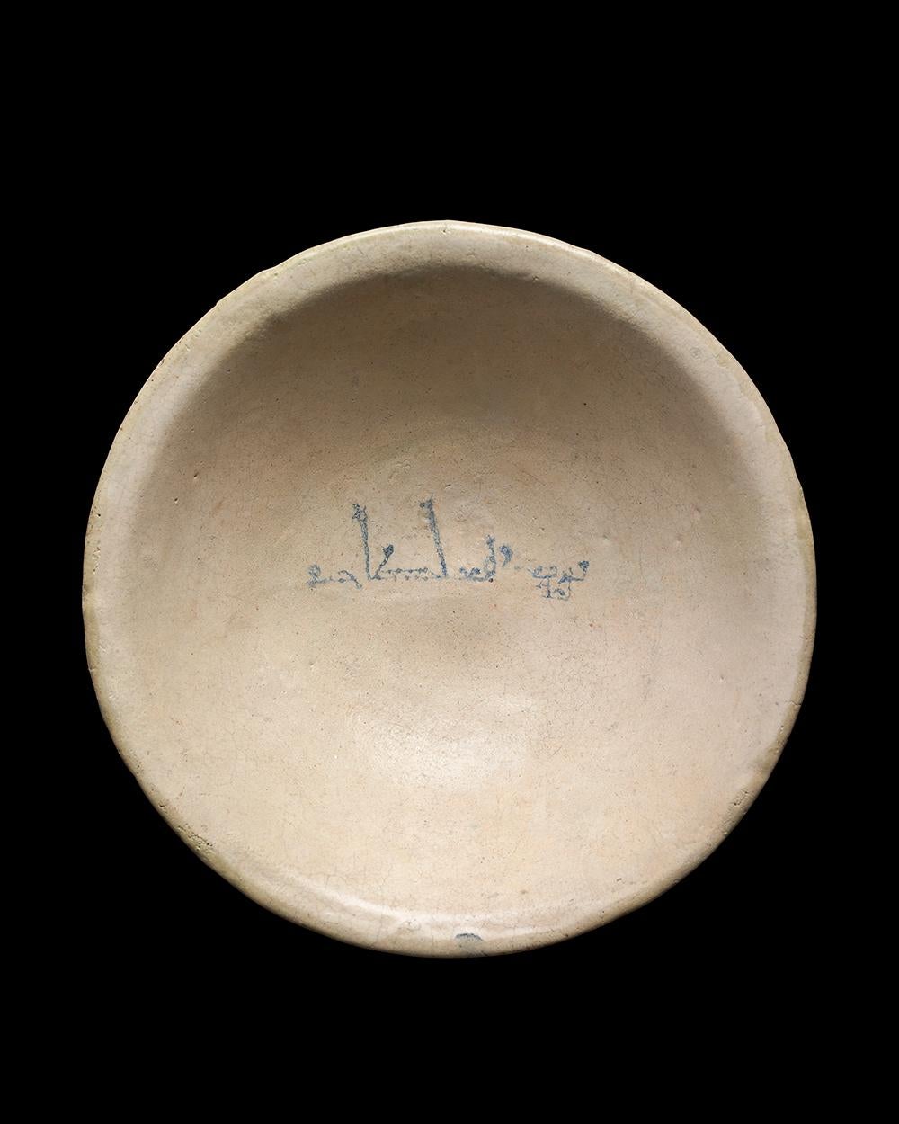 Glazed ceramic bowl with a convex wall and everted rim. With a cobalt blue inscription in the centre which reads, “baraka li-sahibihi” (blessing to its owner). 

Ceramics such as this bowl are among the first examples to incorporate calligraphy as