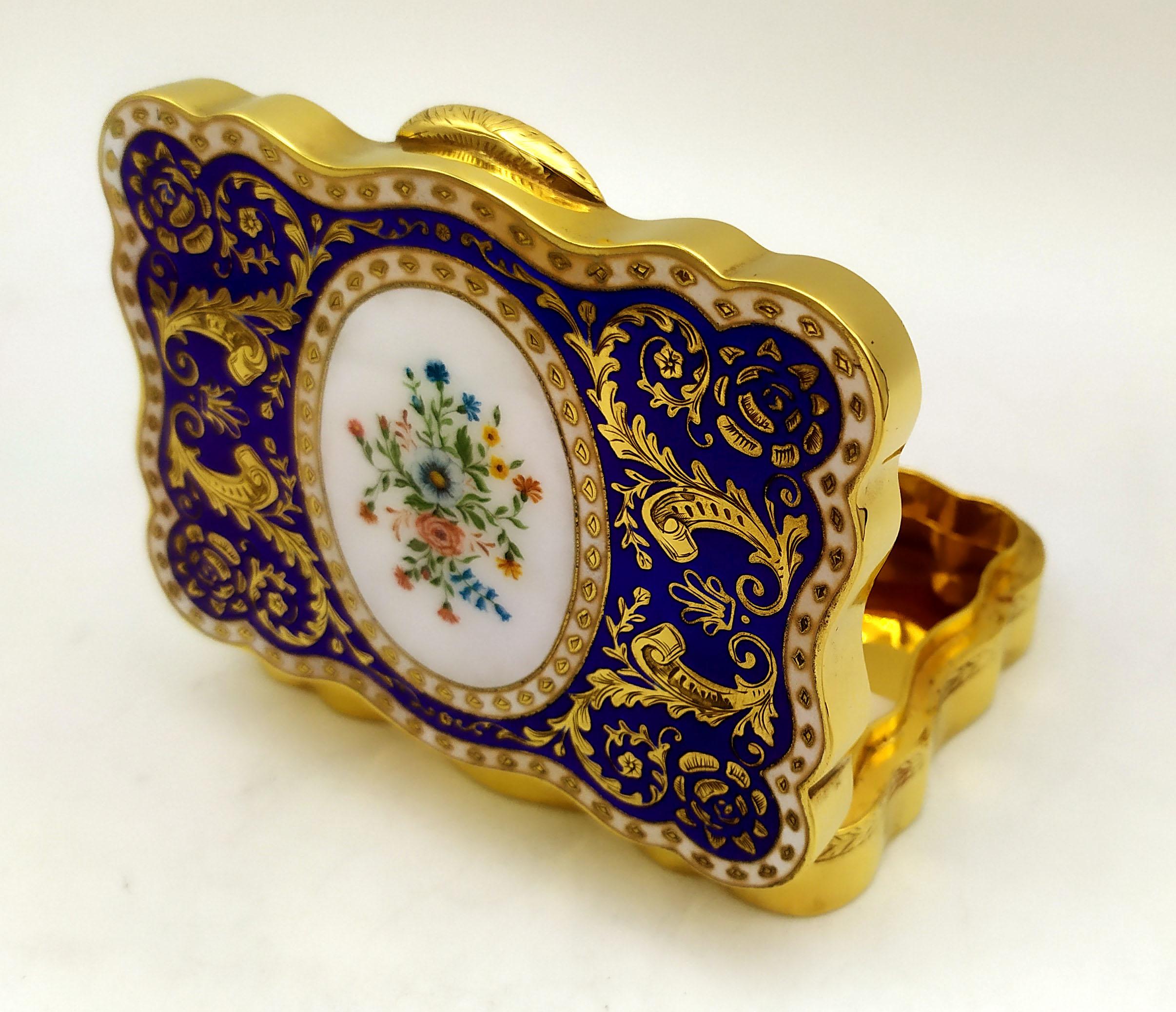 Shaped table box in 925/1000 sterling silver gold plated with fine fire-enameled engraving on the lid and hand-painted floral miniature in 18th century French Empire style. Dimensions cm. 7.8 x 10.5 x 2.5. Weight g. 347. Designed by Franco Salimbeni