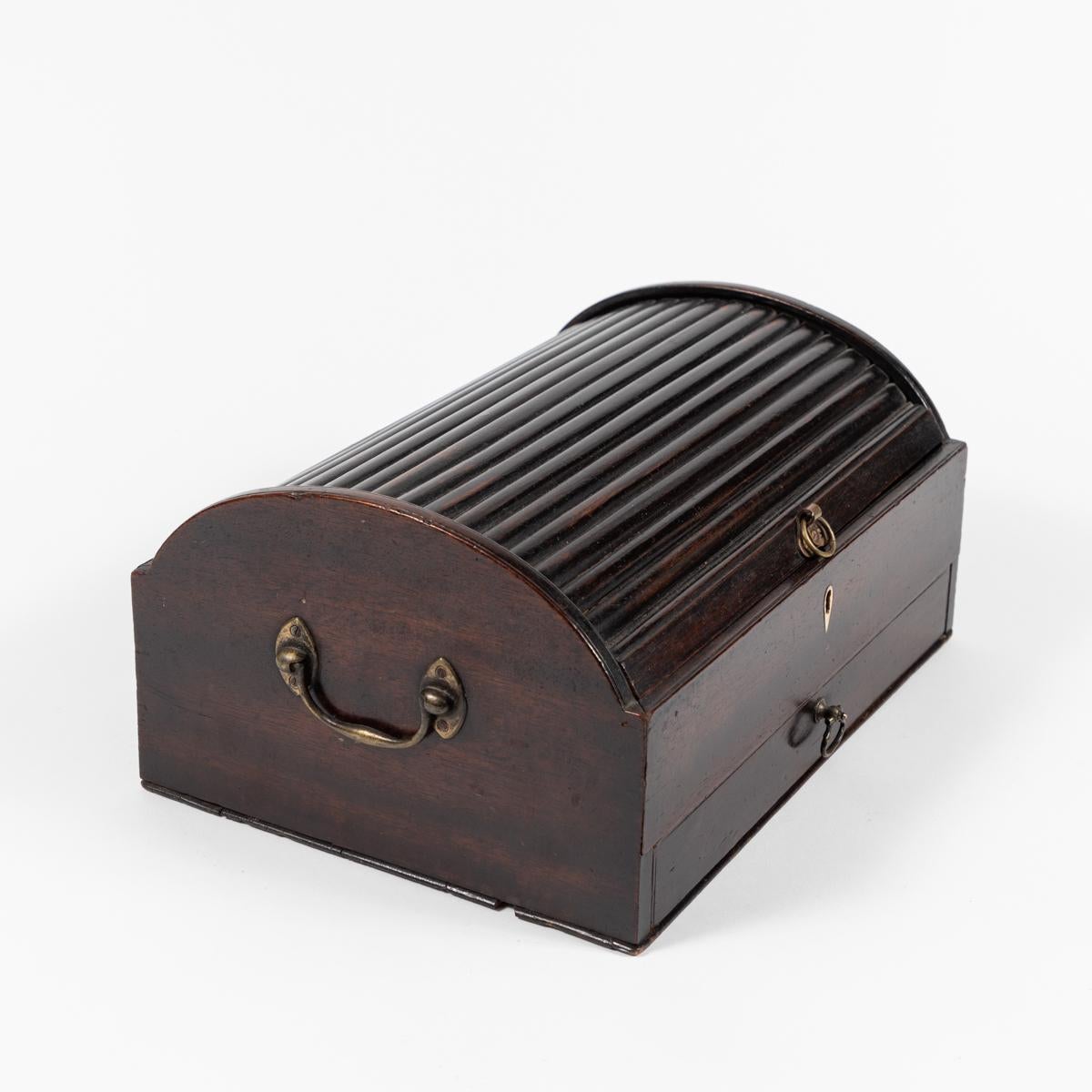 This Tambour top writing box dates from late 19th century England. It features a unique Tambour top a deep brown finish, and would be great for storing jewelry or other small items. 
  