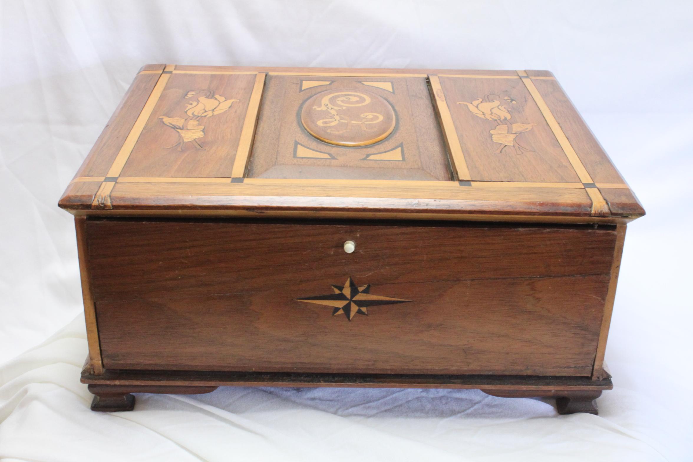This walnut dressing table box features inlays to each surface, most in the Art Nouveau style. On the lid, flanking the central cartouche, are two representations of tulips and in the centre are the letters 