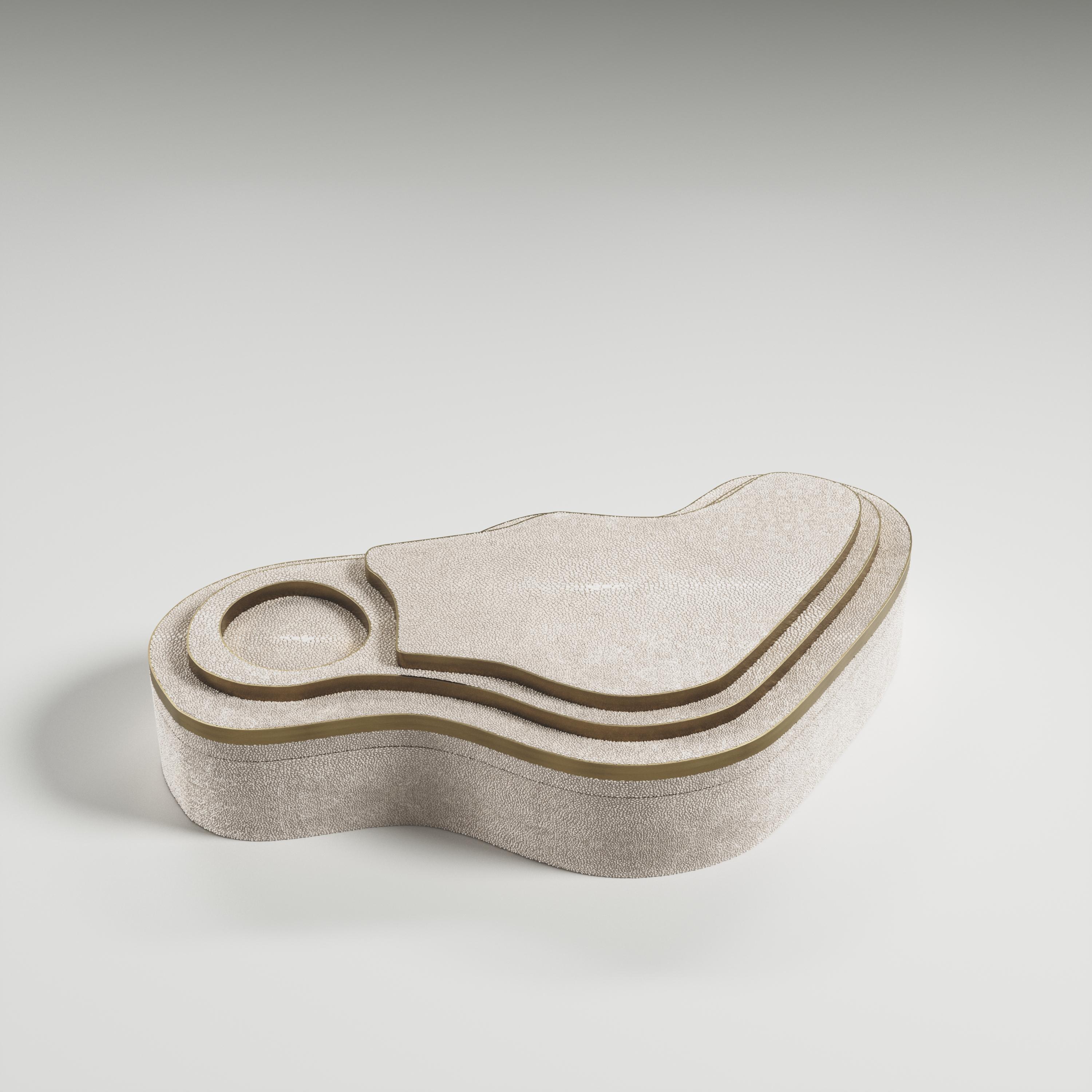 Die Maskenbox mit Relief von Kifu Paris ist ein vielseitiges und organisches Stück. Die amorphe Platte und der Sockel sind mit einer Mischung aus cremefarbenem Chagrin und Messing in Bronze-Patina eingelegt. Dieses Stück wurde von Kifu Augousti, der