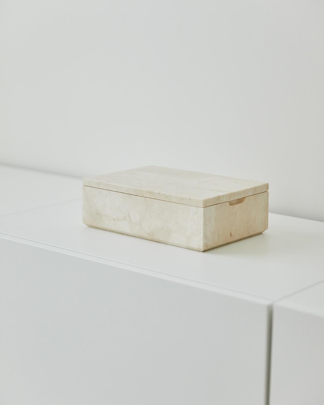 A box with a lid that is made from one solid block of Italian travertine stone. Features a beveled base and cut away to easily remove the lid. Honed smooth finish inside and out with an engraved logo on both the underside of the lid and the
