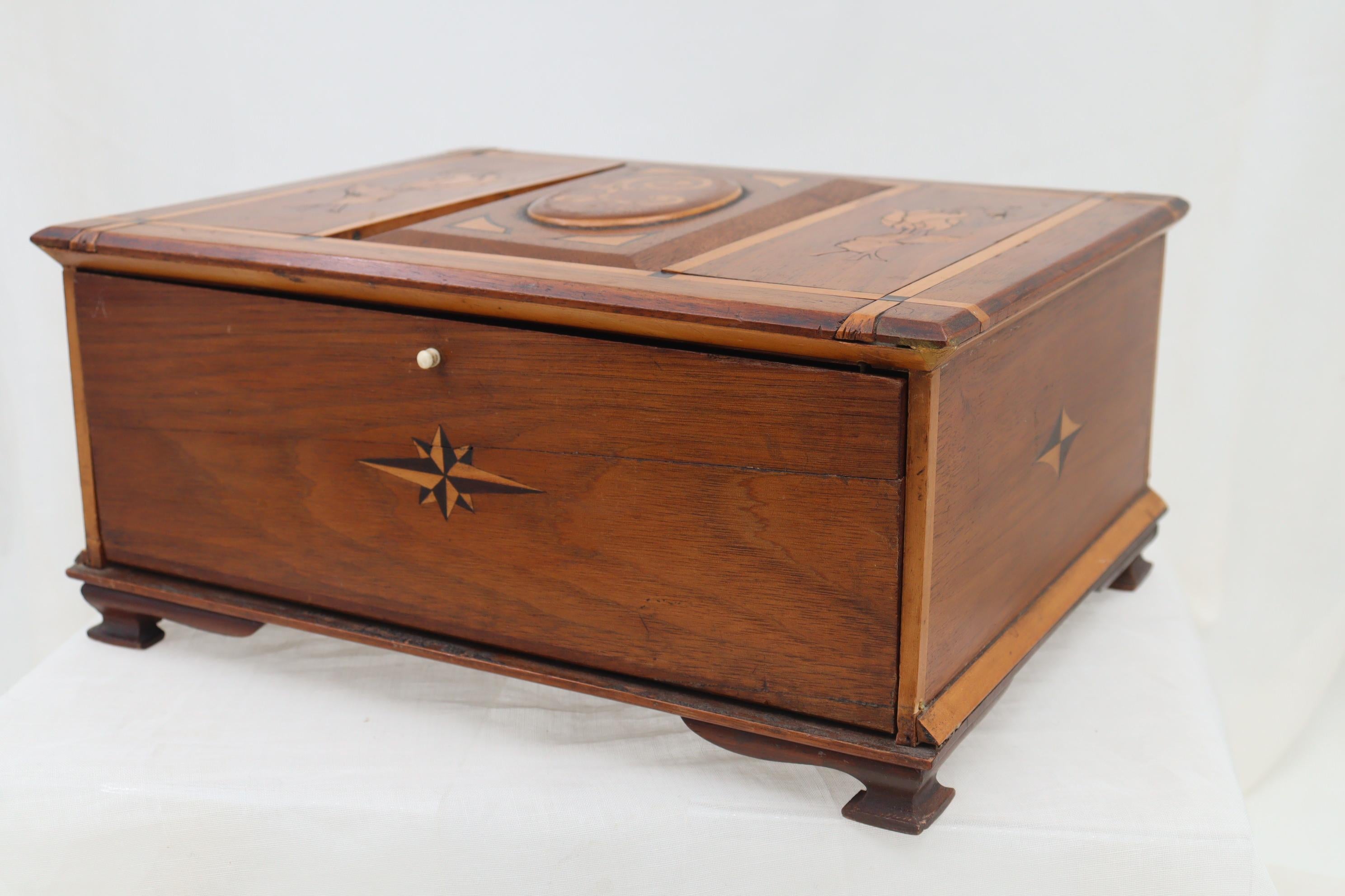 This walnut dressing table box features inlays to each surface, most in the Art Nouveau style. On the lid, flanking the central cartouche, are two representations of tulips and in the centre are the letters 