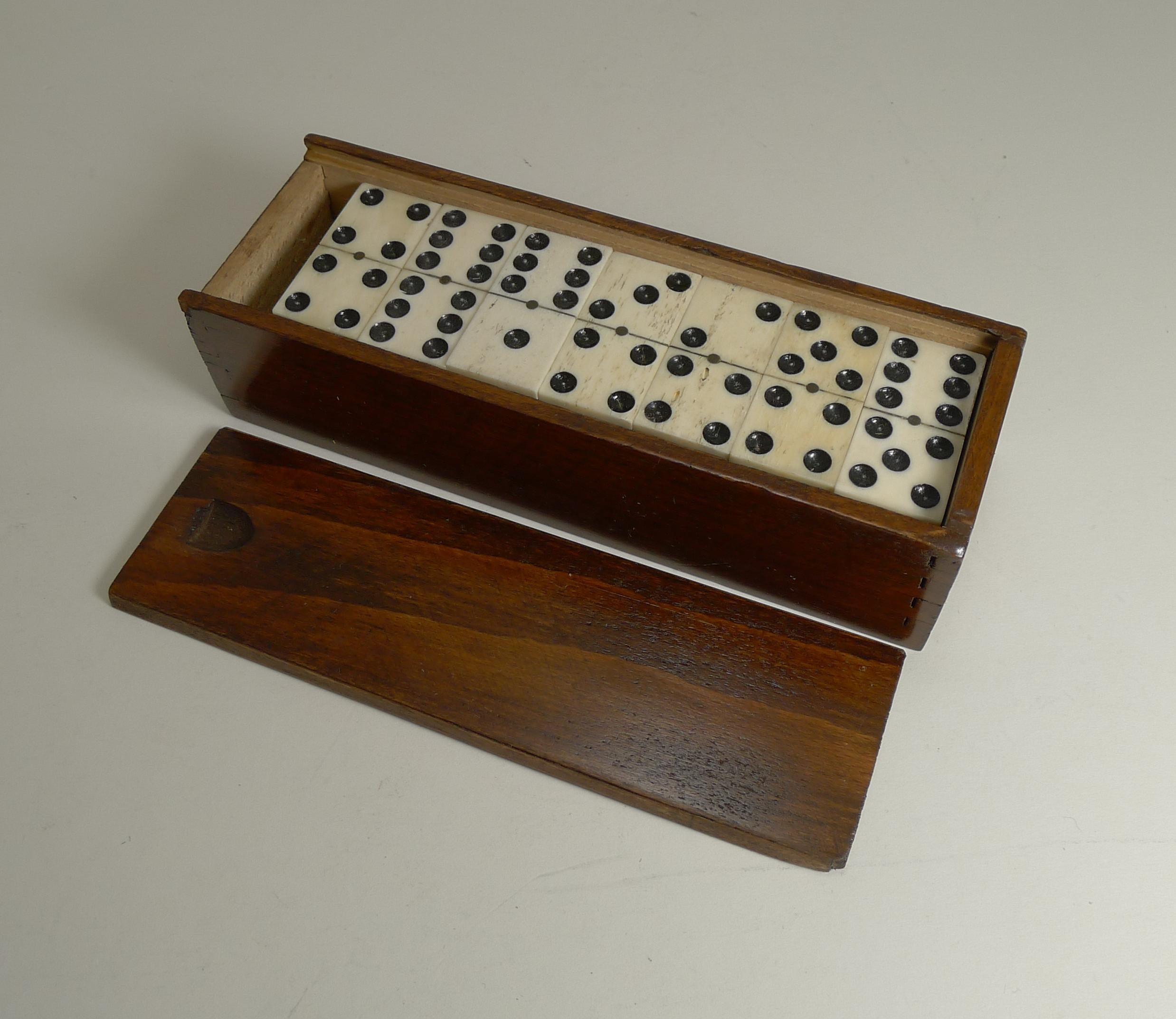 A charming set of late Edwardian dominoes or dominos, all in good condition with a handsome polished wooden storage box with a sliding lid.

The bone and ebony pinned together with small brass pins.

The box measures 7 5/8