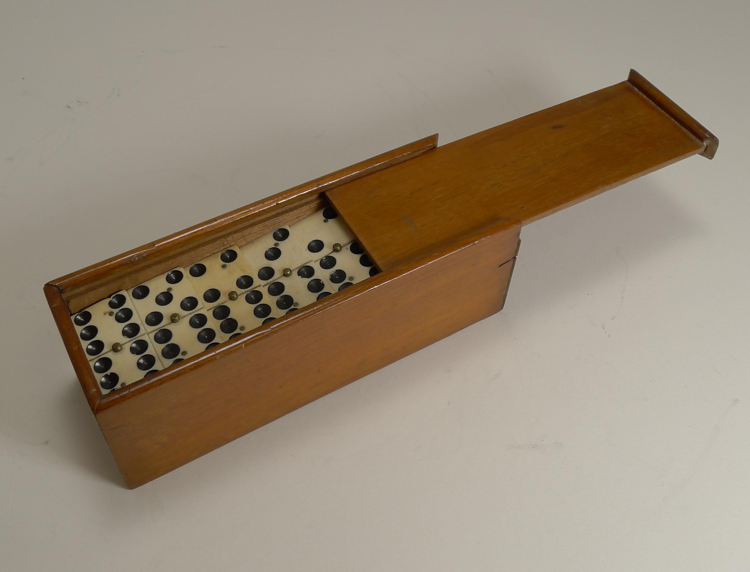 A charming set of late Edwardian dominoes or dominos, all in good condition with a handsome polished wooden storage box with a sliding lid.

The bone and ebony pinned together with small brass pins. The box measures 6 5/8