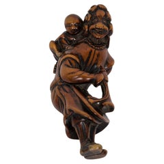 Netsuke de madera de boj que representa a un ducho con un niño y una trompeta