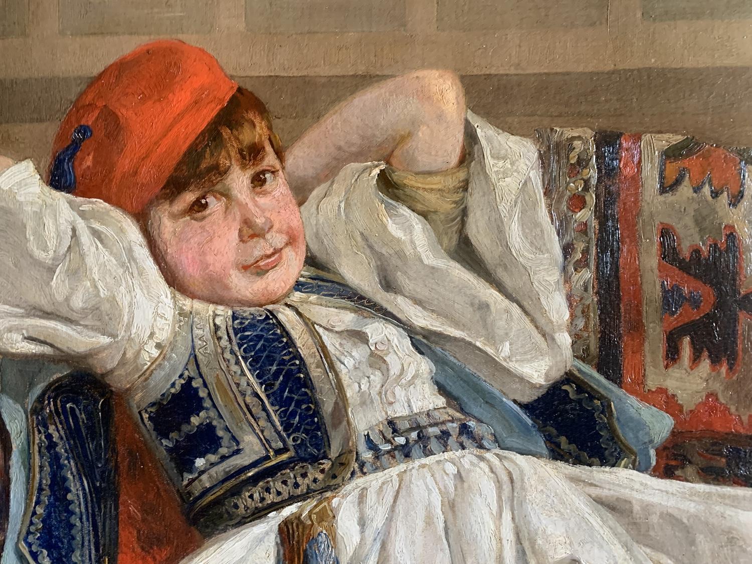 Young boy dressed as an Evzone (elite light infantry battalion of the Greek army, currently assigned to guard the presidential palace in Athens), lying on a sofa, a hookah at his feet. He is dressed in the traditional skirt, the fustanelle, wearing