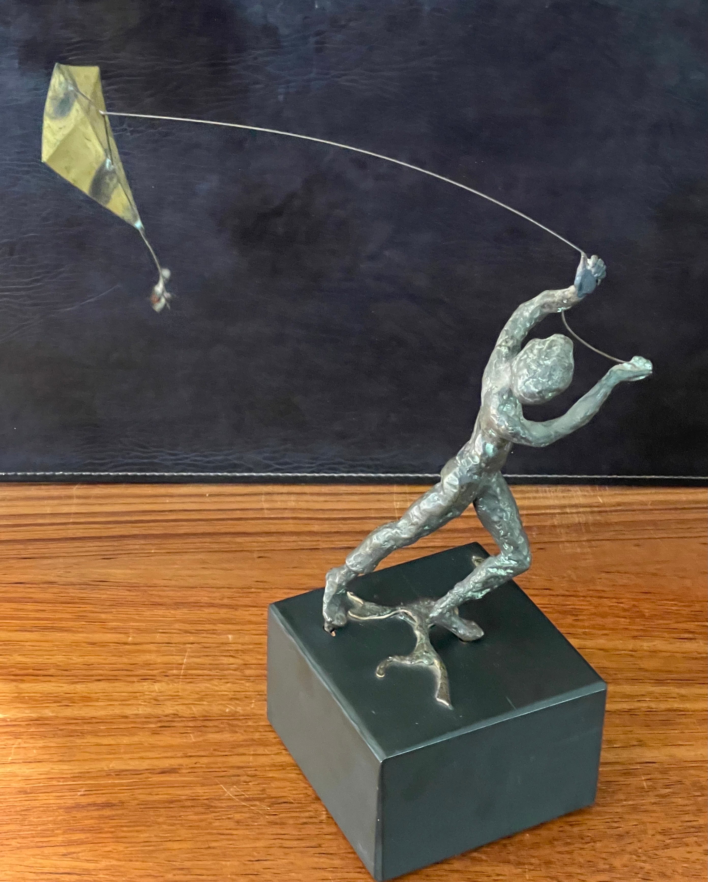 A really cool boy flying a kite bronze on black wood block sculpture by Curtis Jere, circa 1969. The piece is in very good vintage condition and measures 14