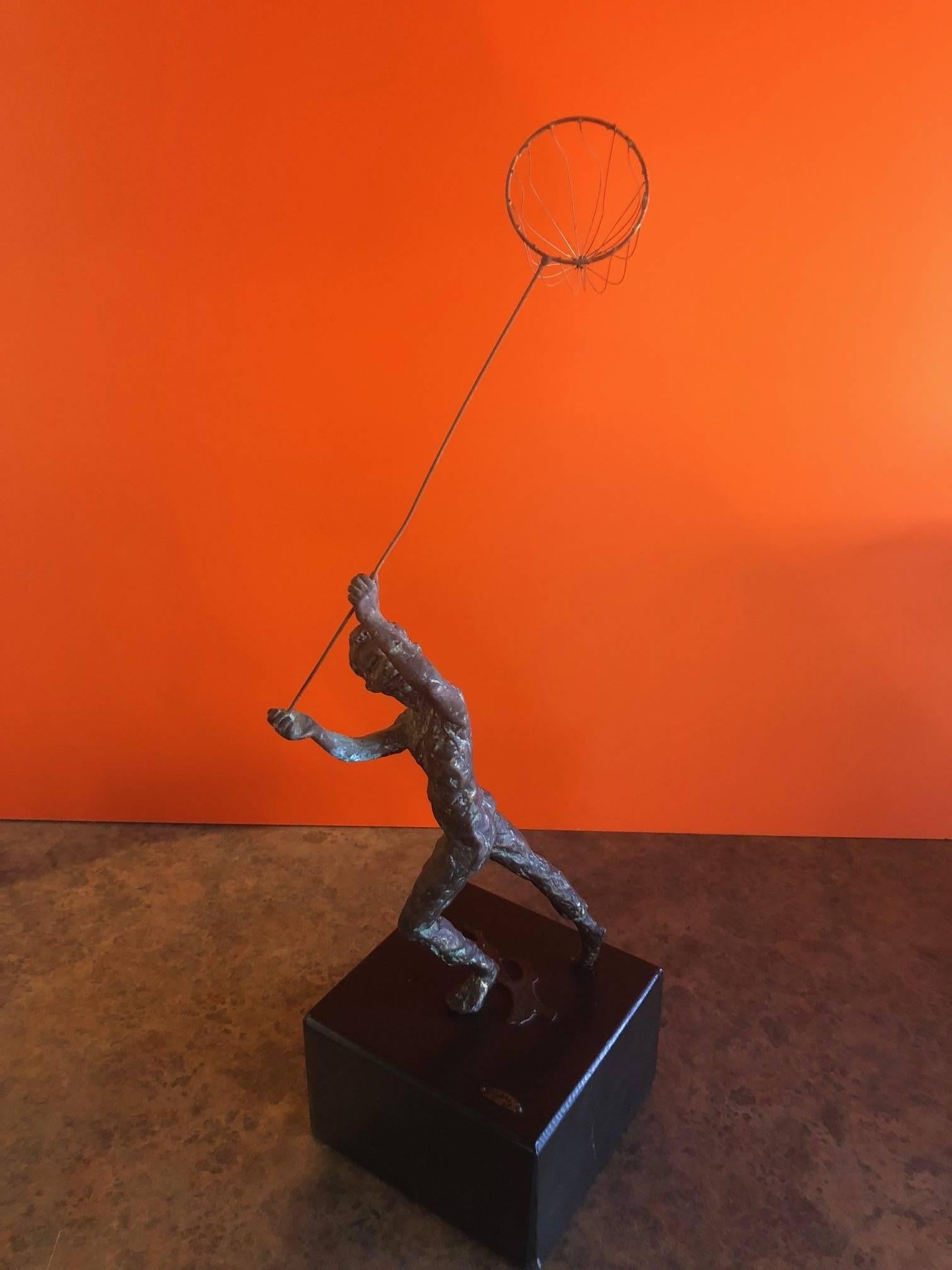Midcentury boy with butterfly net bronze statue on a black wood base with plaque signed by C. Jere, circa 1969. The piece is in very good vintage condition with a nice patina.