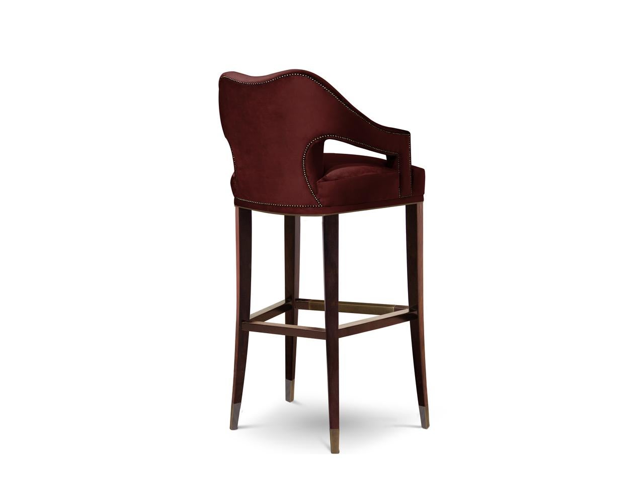 Symbol of knowledge and rebirth, Nº20 Bar Chair was raised through a long journey of 24 prototypes. This fabric chair, upholstered in twill and with legs in ash with walnut stain matte varnish, features a nailhead trim that adds subtle