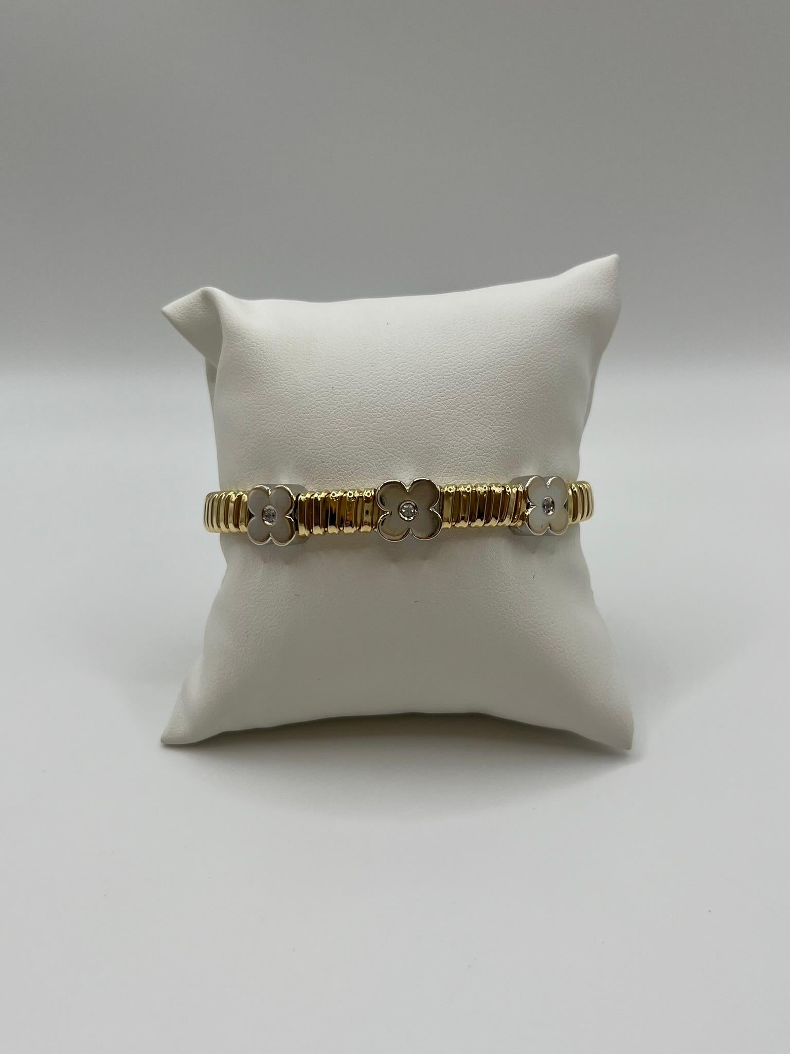 Una elegante pulsera artesanal de oro amarillo de 18 kt, caracterizada por la elaboración Tubogas que garantiza comodidad y resistencia. La estructura tubular está interrumpida por tres elementos decorativos en forma de flor de oro blanco de 18
