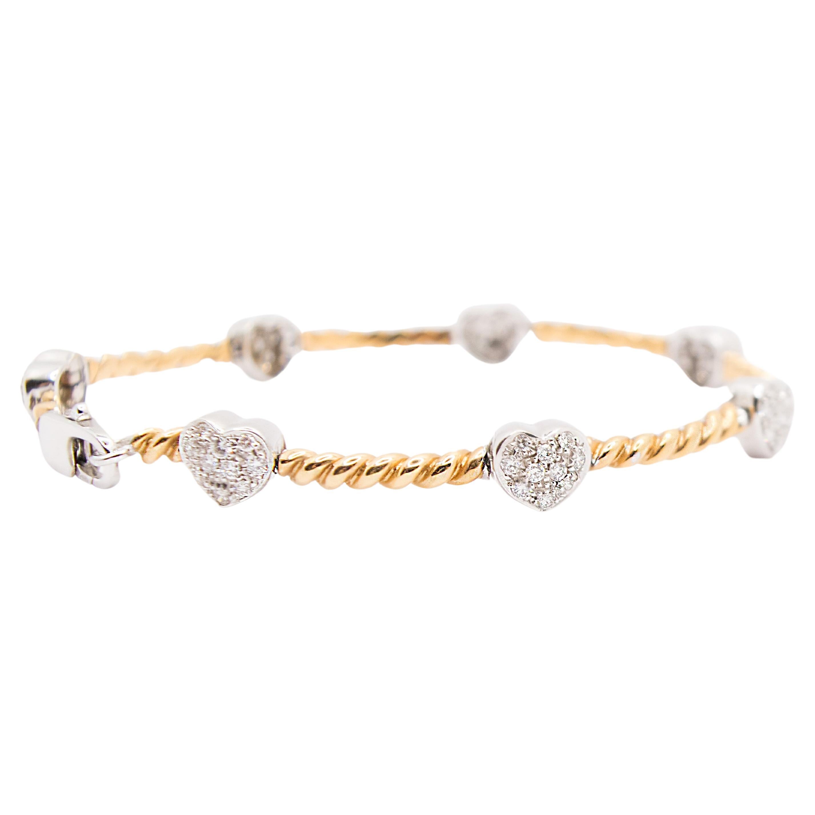 Un bracelet raffiné au design rétro. 
Ce bracelet est en or 18 carats de deux couleurs, or blanc et or rose, pour un poids total de 19,30 g.
La partie en or rose est tressée et entrecoupée de cœurs en or blanc et en diamants. Le poids total des