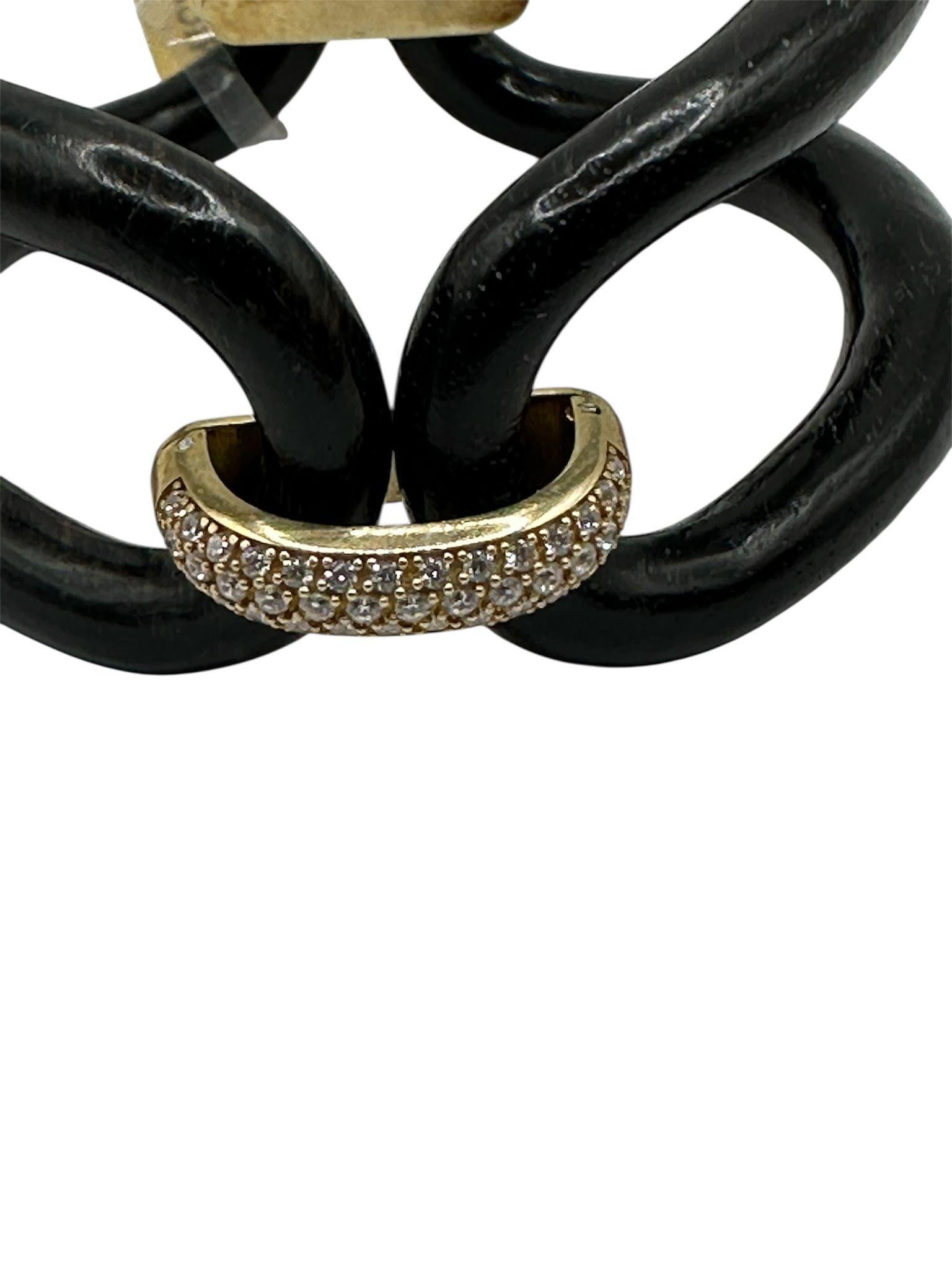 Questo raffinato bracciale unisce la profondità e l��’eleganza dell’ebano naturale alla lucentezza dell’argento dorato e alla brillantezza degli zirconi bianchi, dando vita a un gioiello dal design audace e moderno. Le forme fluide e geometriche si