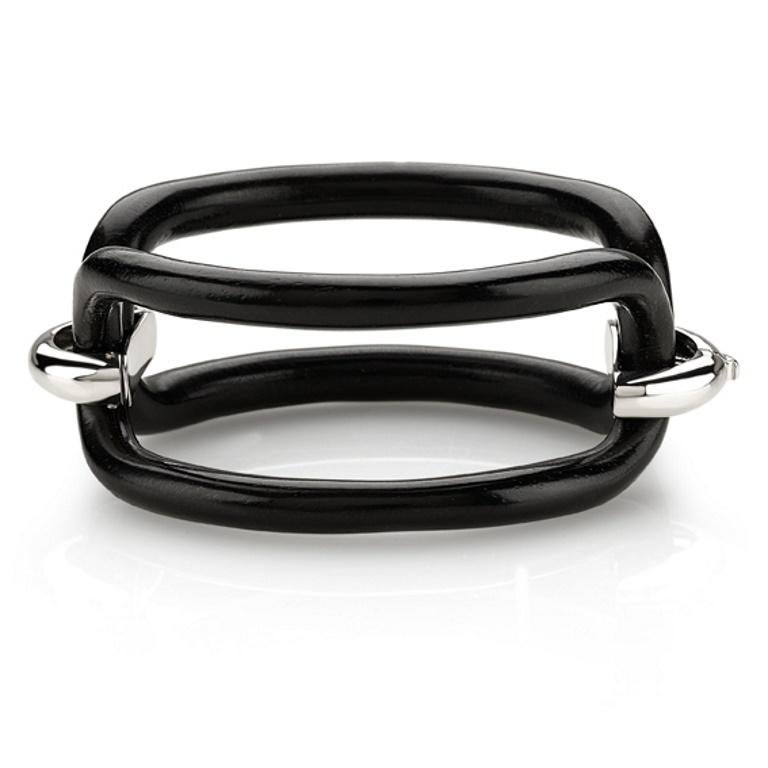 Un gioiello contemporaneo dal carattere deciso, questo bracciale è una vera scultura da indossare. Realizzato in ebano lucidato, dalle superfici sinuose e profonde, è impreziosito da cavallotti in argento rodiato. Il contrasto tra il nero intenso e