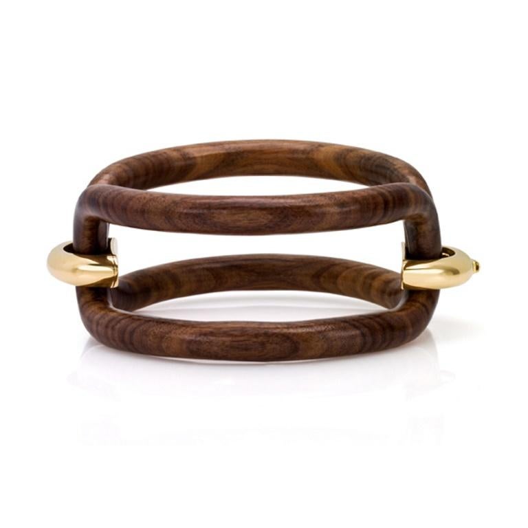 Un gioiello contemporaneo dal carattere deciso, questo bracciale è una vera scultura da indossare. Réalisé en palissandre, dont les surfaces sont sinueuses et profondes, il est orné de cavales en argent élégamment placées dans de l'or 18 carats. Le