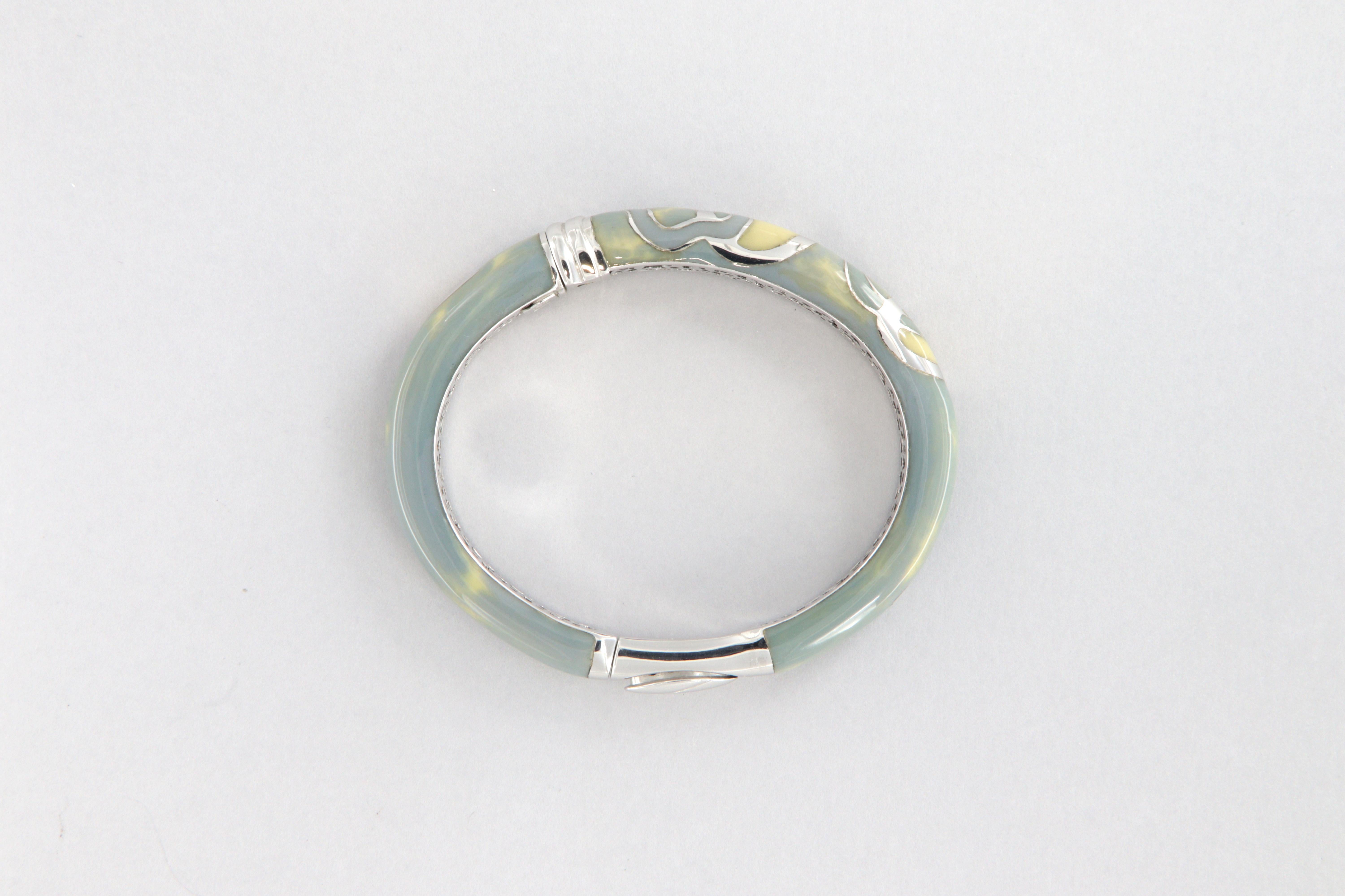 Bracciale rigido La Nouvelle Bague in oro 18 tk, argento 925 e smalto a fuoco

Bracciale rigido con snodo laterale e chiusura a scatto con pulsante. Realizzato in oro 18 kt,  argento 925 sterling e smalto a fuoco lilla con sfumature crema. Motivo