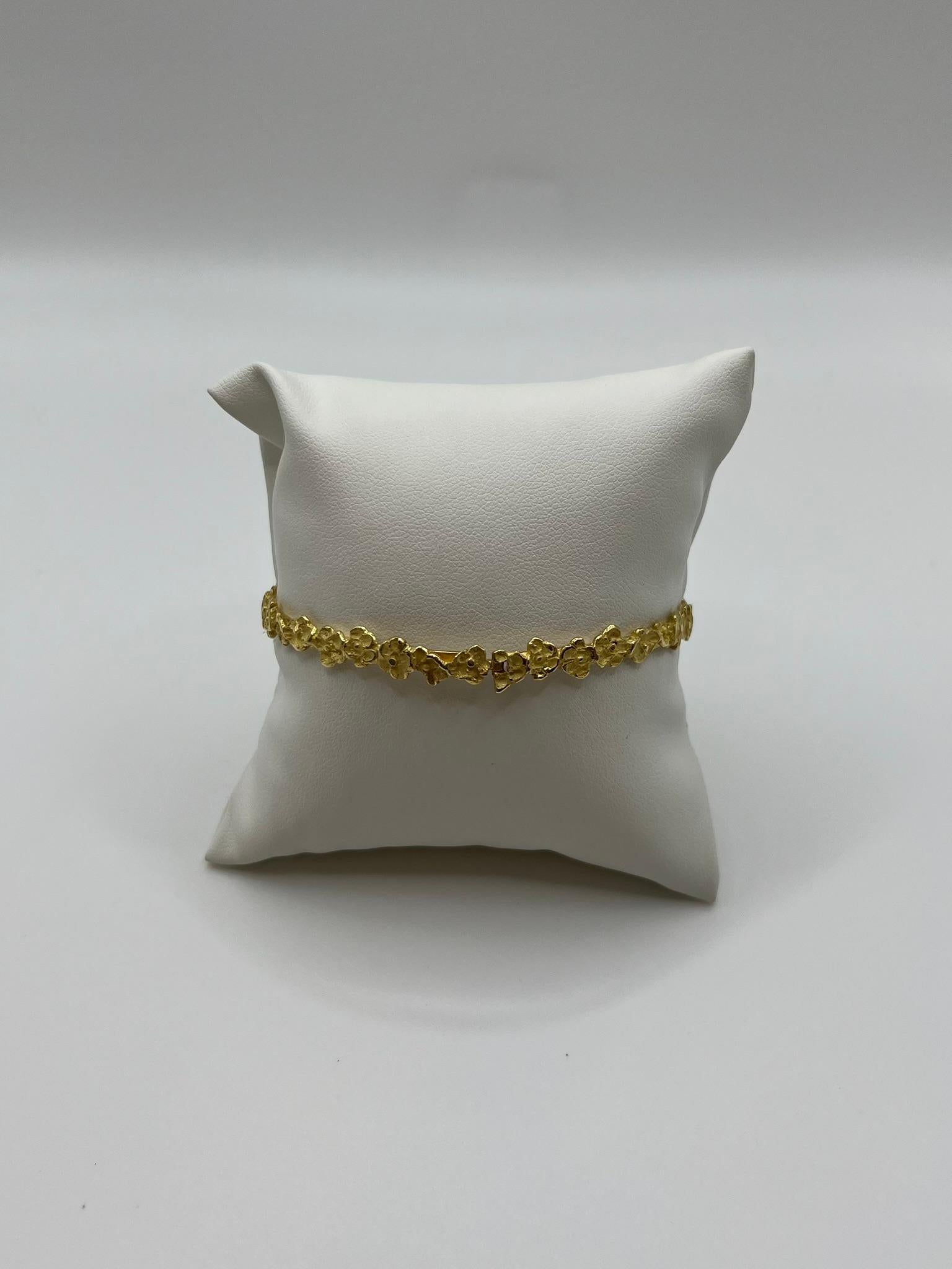 Elegante bracciale semirigido realizzato interamente in oro giallo 18 kt. 750/00. E' stato disegnato e prodotto artigianalmente in Italia e presenta una particolare lavorazione a rilievo che disegna dei fiori lungo tutta la sua lunghezza. Misura 20