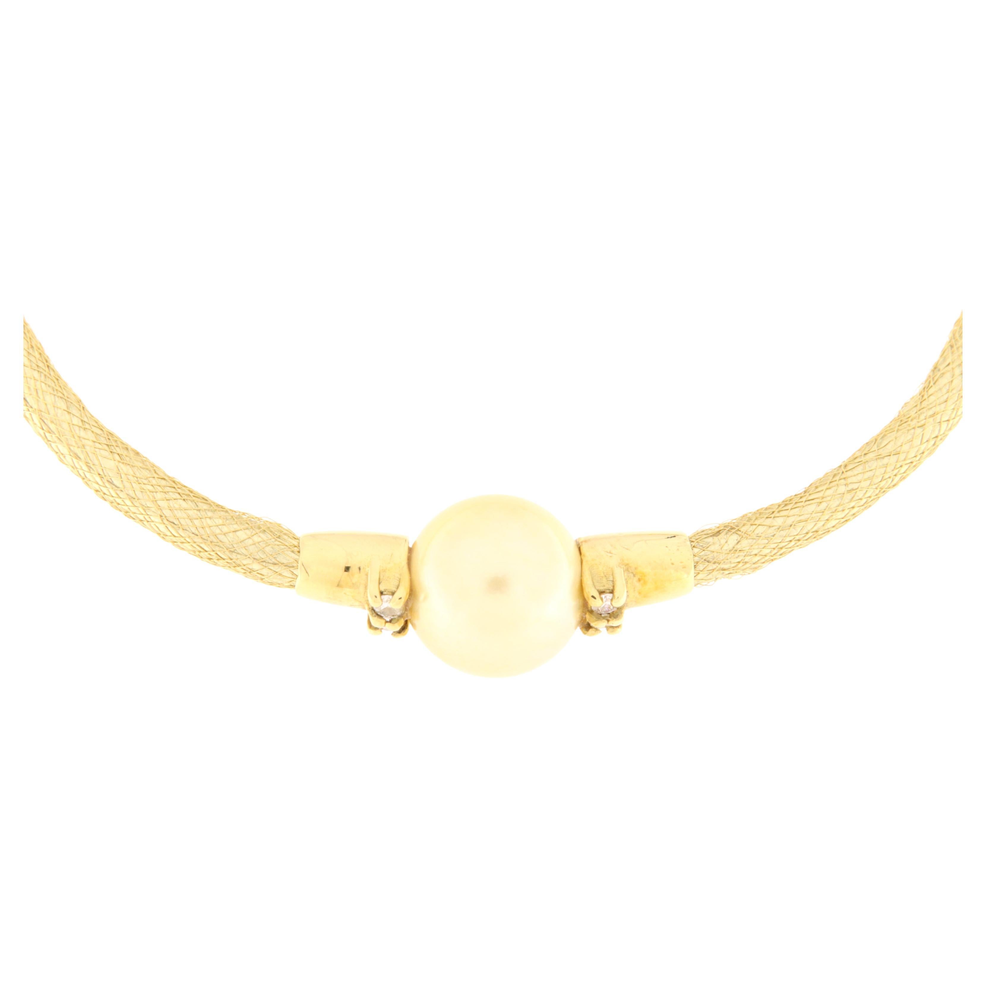 Semi-rigid bracelet made with a gold fabric, yellow gold frame and clasp. Mounted in the center is a beautiful gold pearl embellished with four rhinestones on either side. The same model is also available in white gold with Tahitian gray pearl or