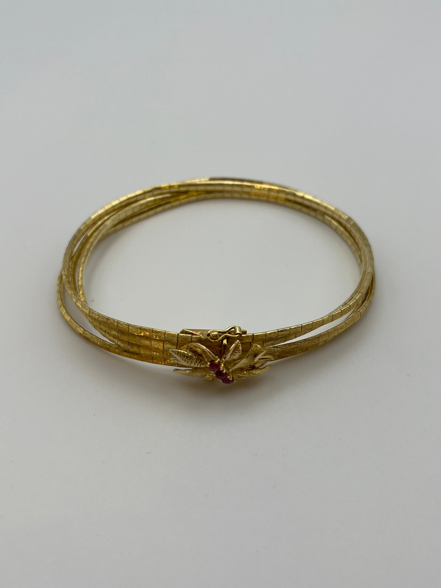 Bracciale multifilo in oro giallo 18 kt. 750/00 realizzato in Italia artigianalmente negli anni '60. Sopra la chiusura presenta una particolare lavorazione a fiore con tre rubini. Usato, ma in ottime condizioni, pari al nuovo.