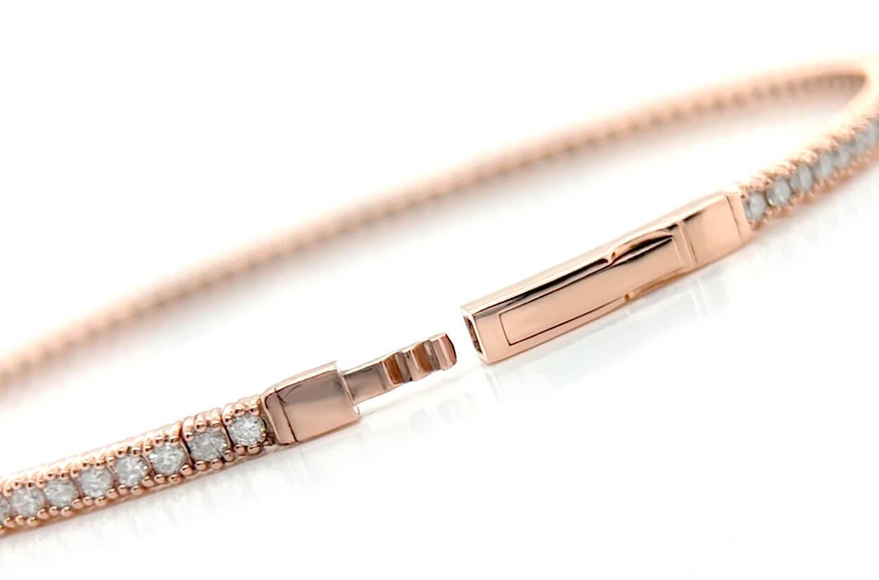 .
This 14kt rose gold bangle tennis bracelet is the epitome of grace and charm. Encircling your wrist in a delicate and feminine embrace, it shimmers with an unbroken circle of round-cut diamonds, exuding a timeless allure. The warm and romantic hue