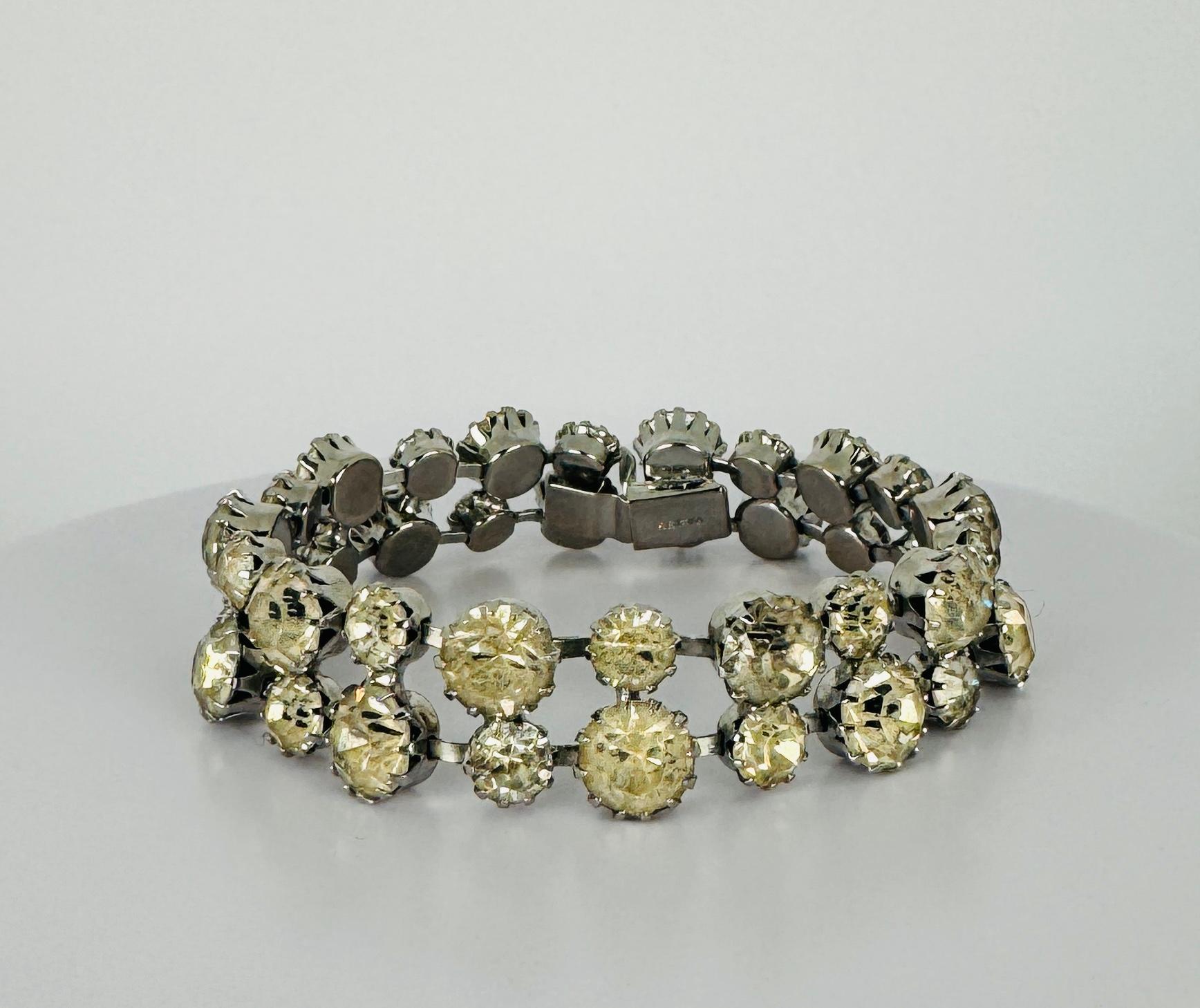 Ce magnifique bracelet en cristal des années 1940 est un véritable trésor vintage. Signé par Weiss, il présente un design en métal argenté serti de cristaux de verre véritables de deux tailles différentes disposés en deux rangées. Le bracelet est