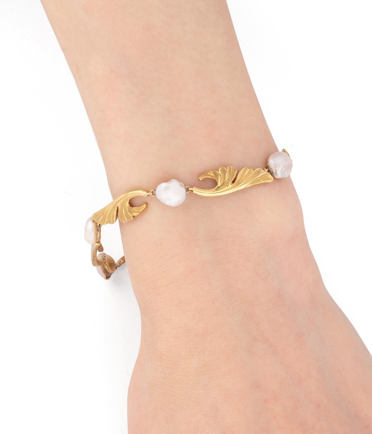 Pulsera Art nouveau en or 18 carats (750 millièmes), formé de feuillage de gingko biloba alterné de perles de culture baroque. À noter fermoir dissimuler dans l'une des feuilles. 

Poids total du bijou : 22,2 g environ.
Longueur 18,5 cm.
Poinçon