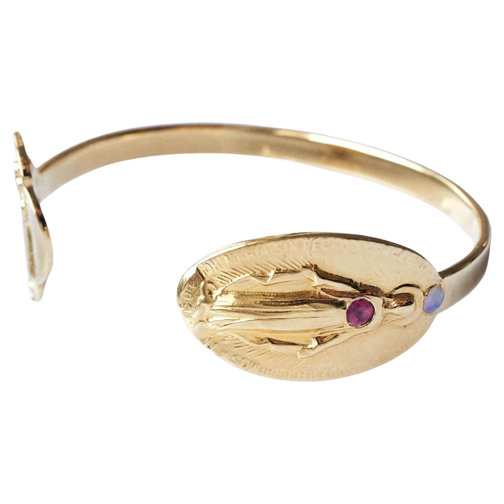 Virgin Mary With Pink Tourmaline set in the Heart and Opal above the head - The bracelet is open and has two medal on each side.
It is a Gold Plated Bracelet Cuff  Bangle 
Designer: J Dauphin


Symbols or medals can become a powerful tool in our