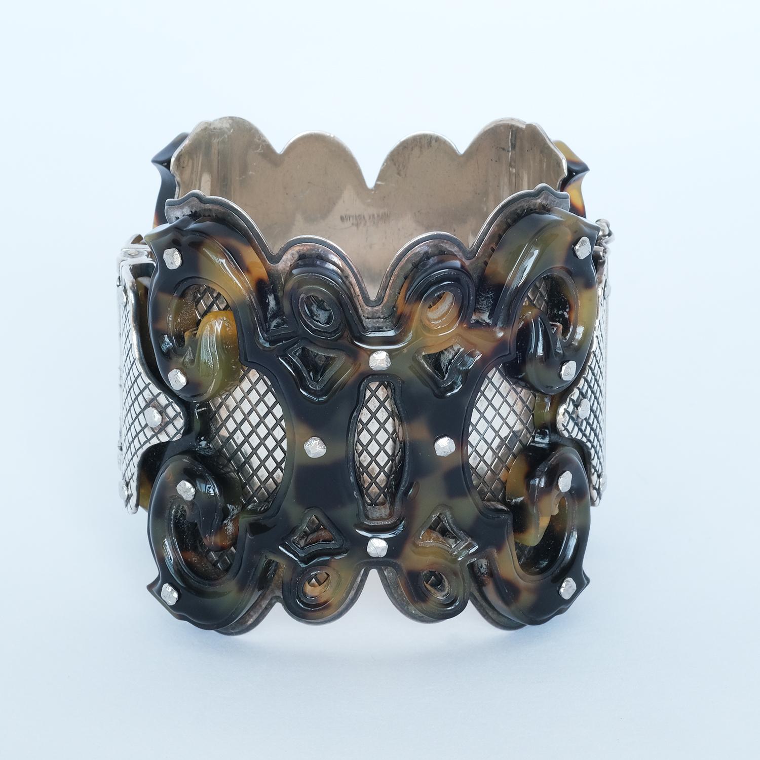 The base of this bangle is sterling silver, and upon the silver there is a beautiful layer of brown acrylic, formed in an ancient gothic style. The acrylic pattern is also nicely complemented by the metal nails attaching the acrylic to the silver