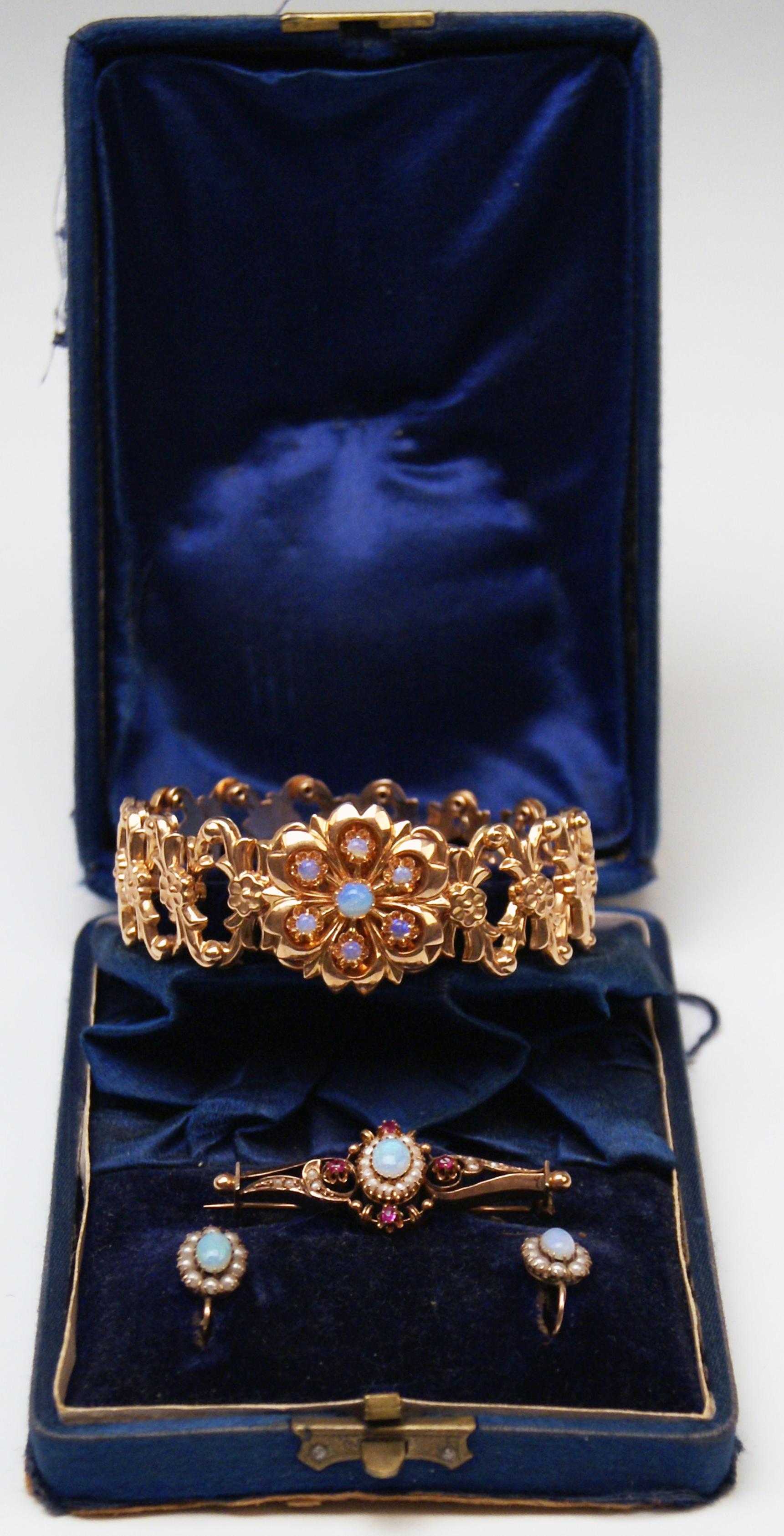 Hochviktorianisch (= Wiener Historismus)  Goldschmuck-Set,  bestehend aus:
-- 1 Armband
-- 1 Brosche
-- Paar Ohrringe

Die Teile dieses Sets sind aus 14 Karat Roségold 585 gefertigt / verziert mit:
-- Opale
-- Süßwasserperlen 
--