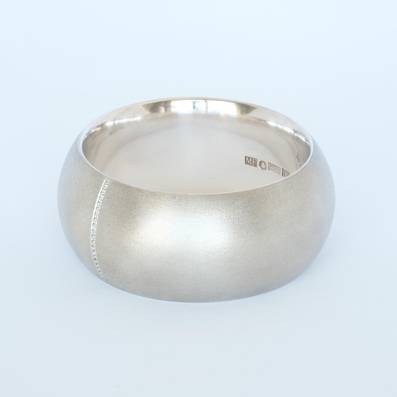 This sterling silver and synthetic diamond bangle is both solid and wide. It has a silky matt surface and a ribbon of 23 synthetic diamonds running across.

This bangle brings your thoughts back to the lovely eighties and it manages to communicate