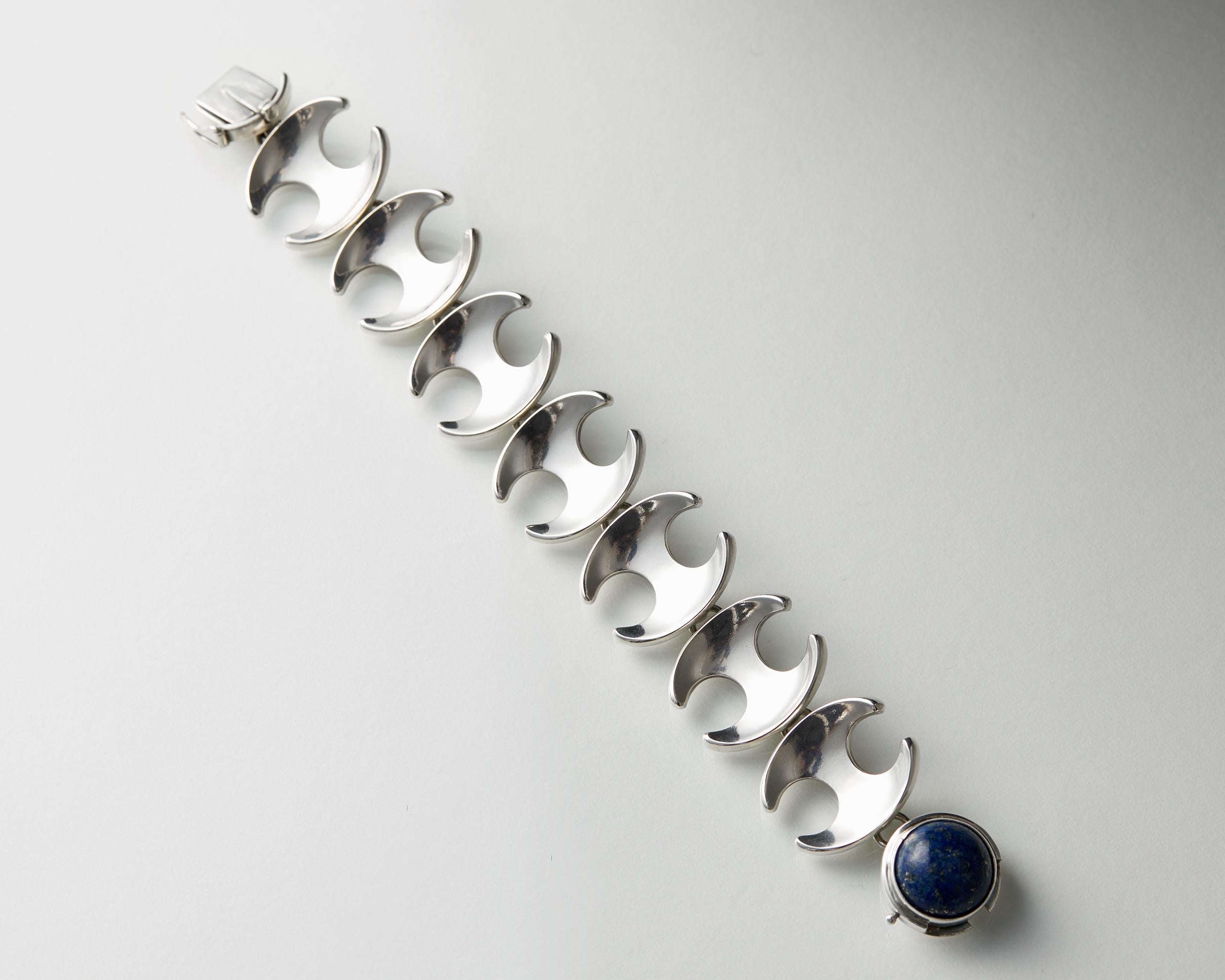 Sterling silver and lapis lazuli.

Stamped: Georg Jensen, 925 sterling, Denmark, 130 B

L: 19.5 cm/ 7 3/4