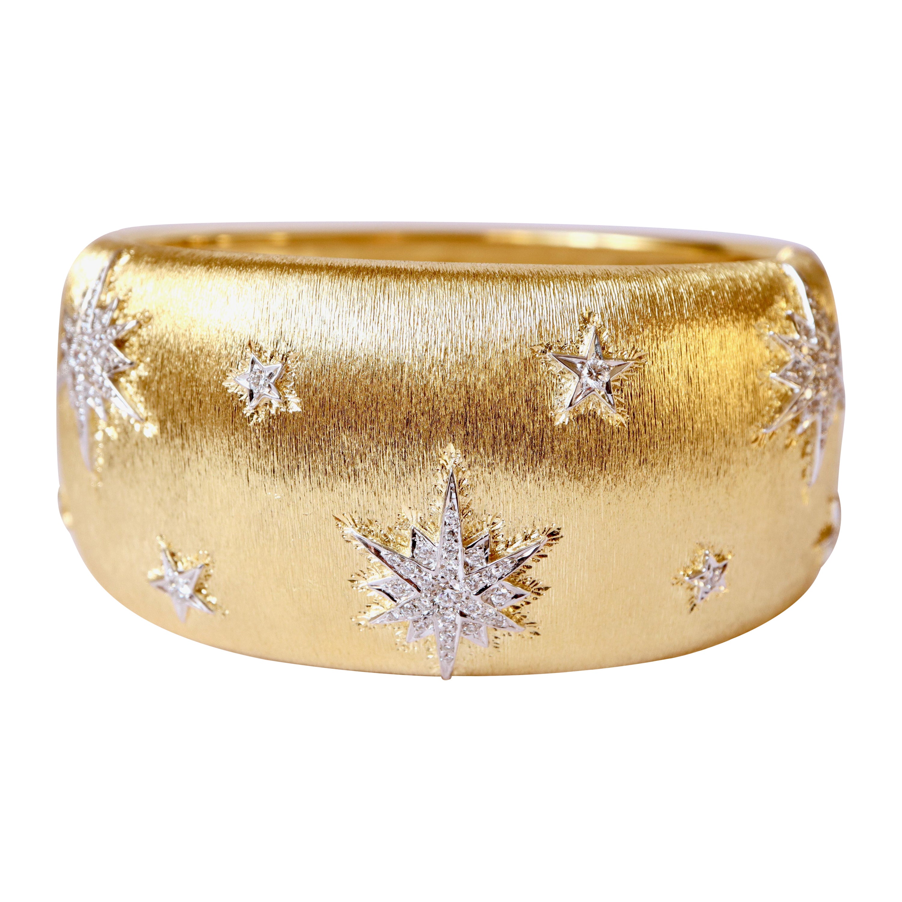 Bracelet in Yellow gold 18 kt and white gold 18 kt and diamond with star motif 
Rigid opening bracelet in 18 kt yellow gold, grooved, domed with a pattern of stars or snowflakes in 18 kt white gold applied, set with diamonds, 3 of which are large