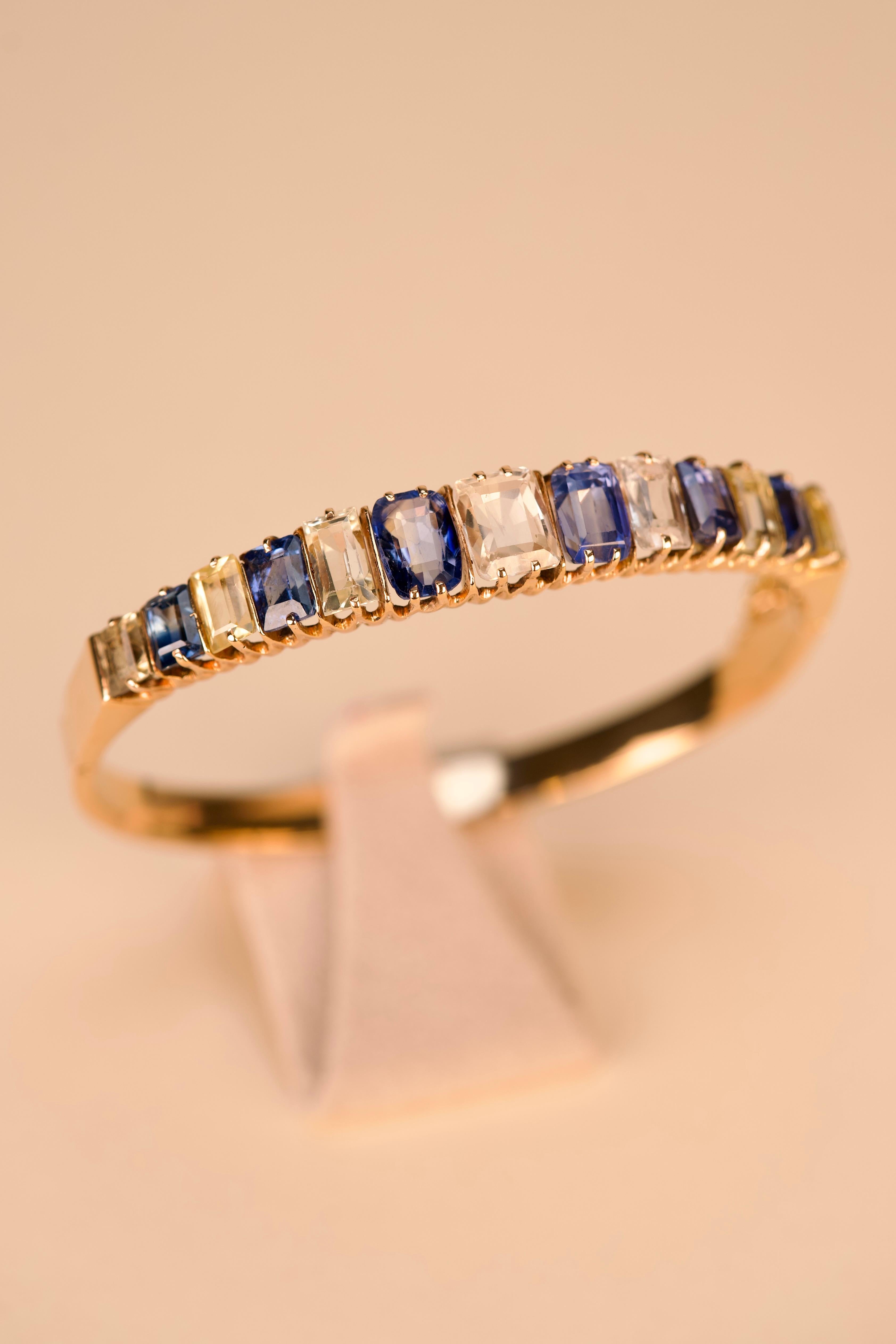 
Pulsera rígida de oro amarillo de 19,2 kt - 800 ‰ , engastada con 6 zafiros azules y 7 zafiros amarillos que suman aproximadamente 16,8 ct. 6 cm de diámetro interior, con cadena de seguridad. Portuguesa, con la marca de ensaye de Lisboa (1938-1984)