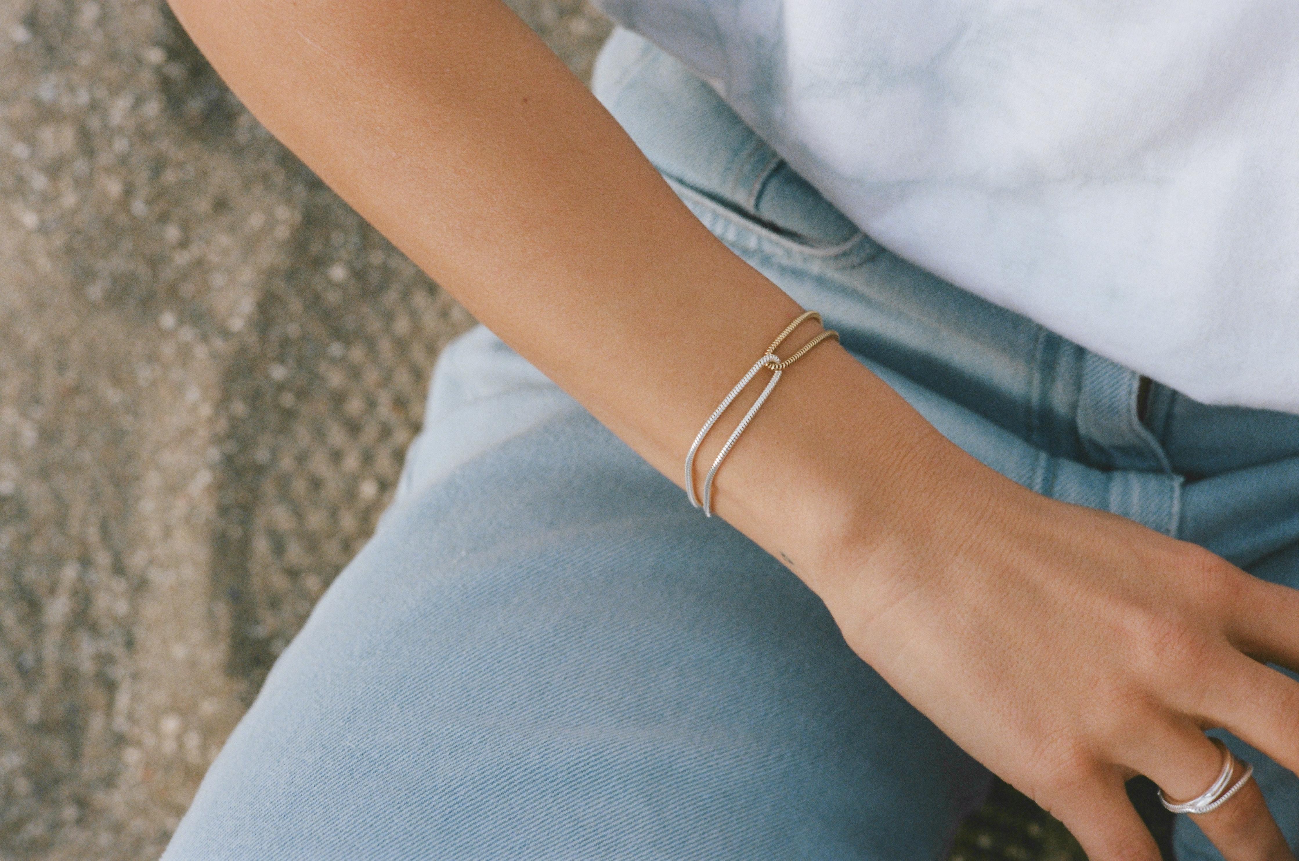 This bracelet consists of two chains, one silver and one yellow gold plated, looped through each other. This is a very graceful piece inspired by nature's delicate shapes and movement, bringing elegance to any outfit.

Hand-crafted by local skilled