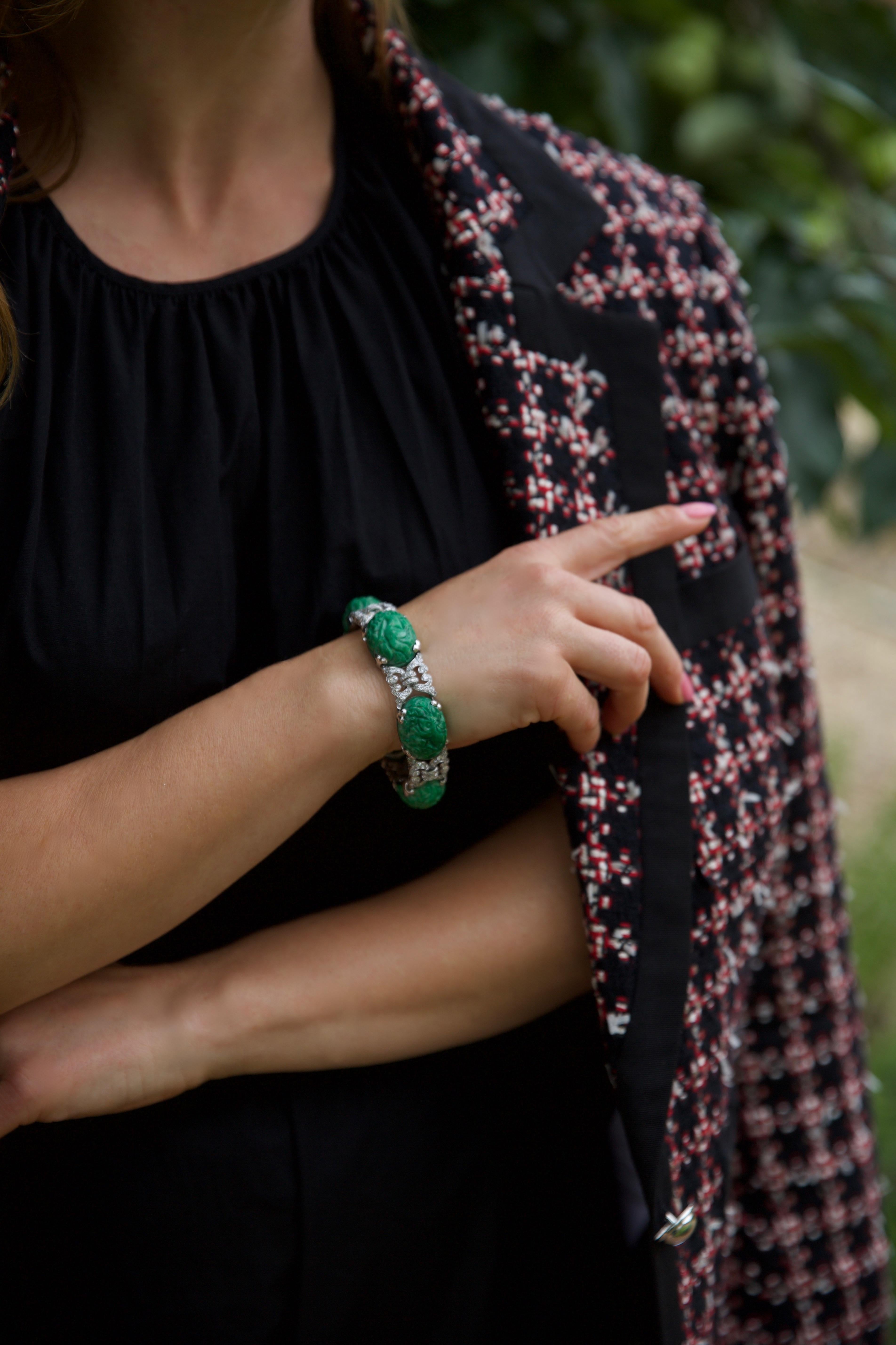 Ein auffälliges Platinarmband mit sechs fein geschnitzten ovalen Jadeplatten, die mit traditionellen Motiven verziert sind. Die leuchtend grüne Jade ist in gegliederte Glieder eingefasst, die mit Diamanten im Brillantschliff besetzt sind, wodurch