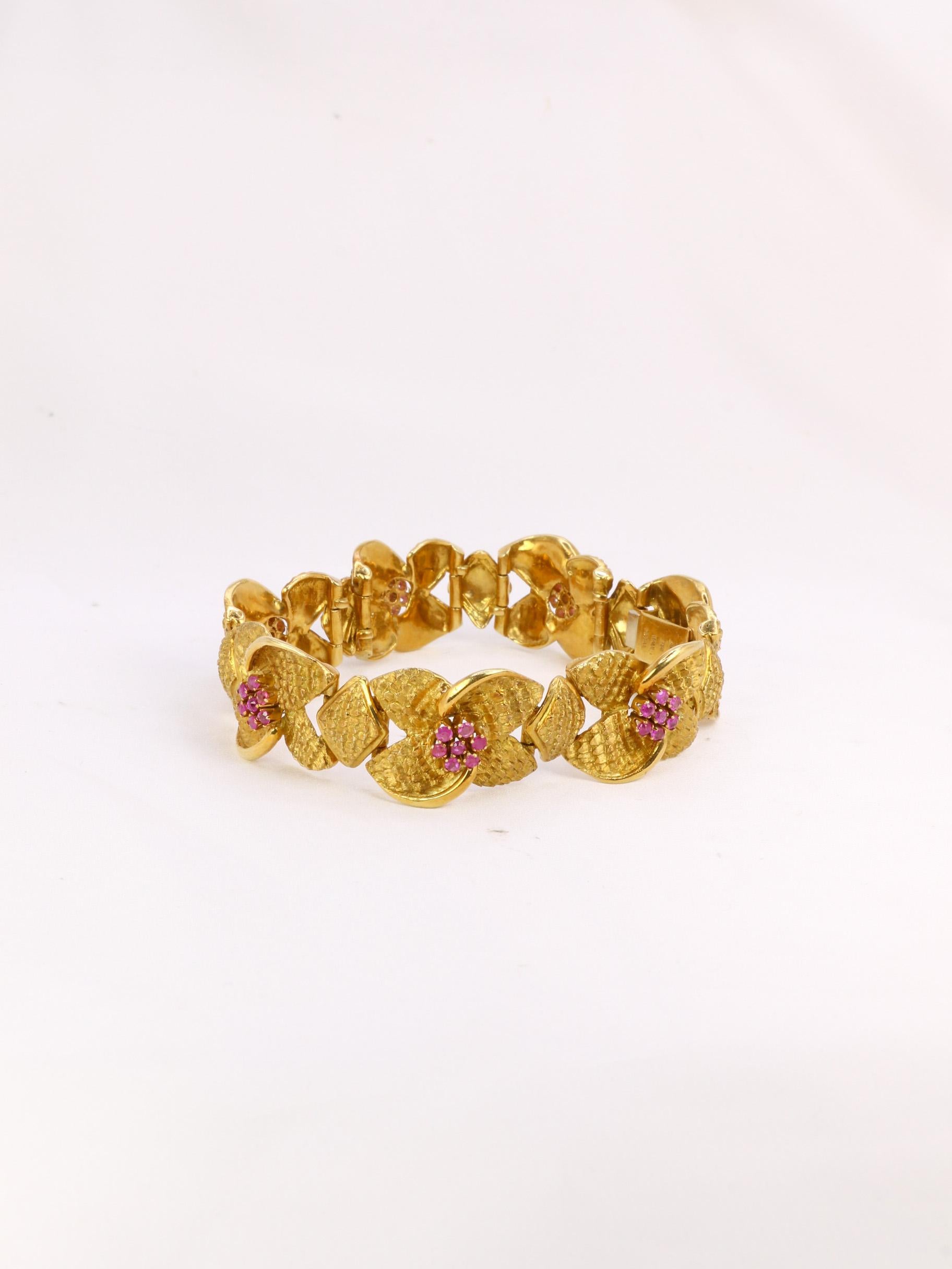 Armband aus 18-karätigem Gold (750°/°°), bestehend aus braunen Gliederarmbändern, die mit Blumen verziert sind. Die Blütenstempel sind mit kleinen Rubinen versehen. Ein italienisches Werk von hervorragender Qualität aus den 1960er Jahren. Signé du