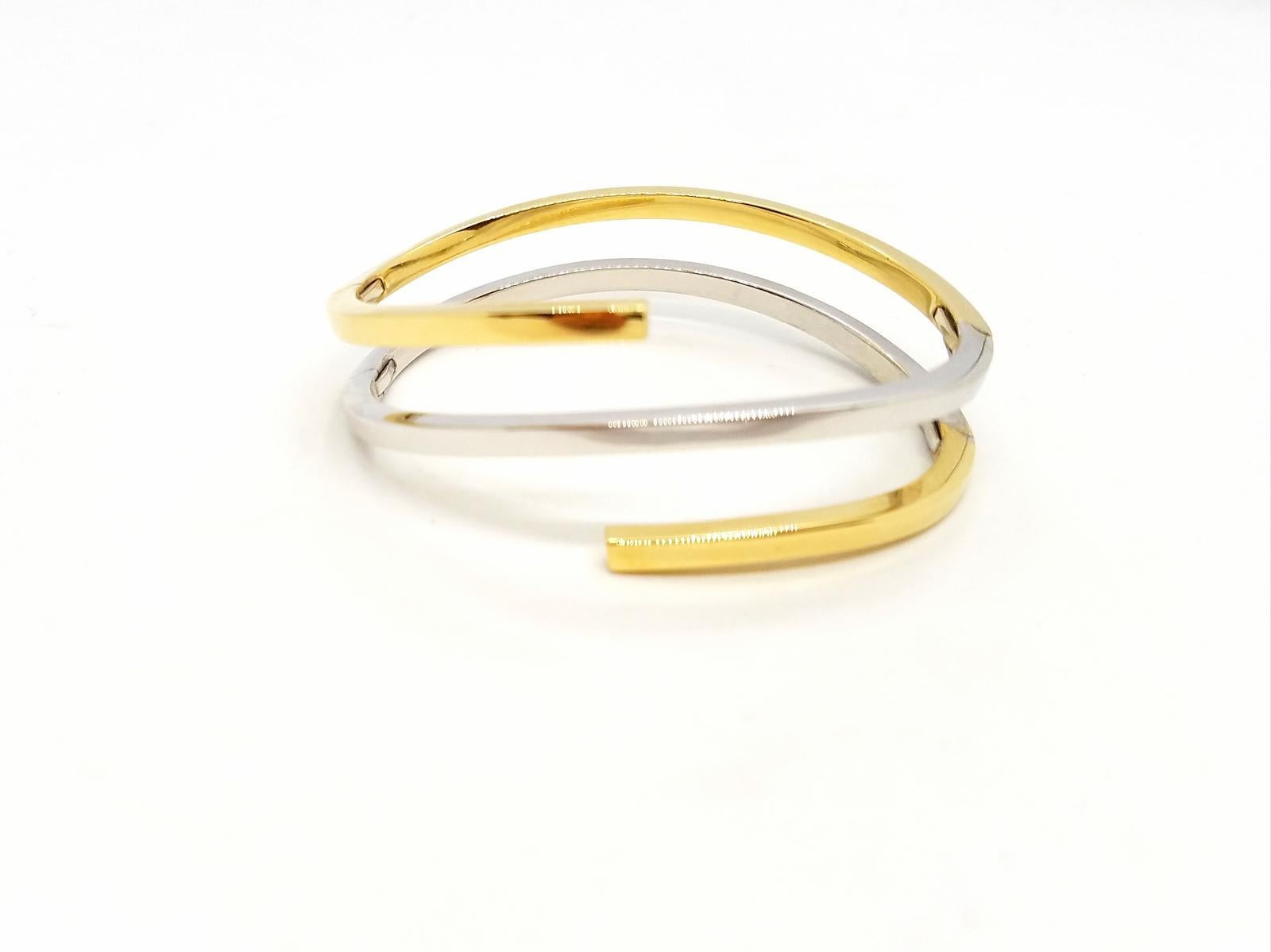 Bracelet rigid hinged. two colors. white and yellow gold 750 mils (18 carats). opening into 5 parts. square wire. size: 19 cm. total width: 2.6 cm. width of a wire: 0.34 cm. total weight: 26.22 g. punch on the end. excellent condition
