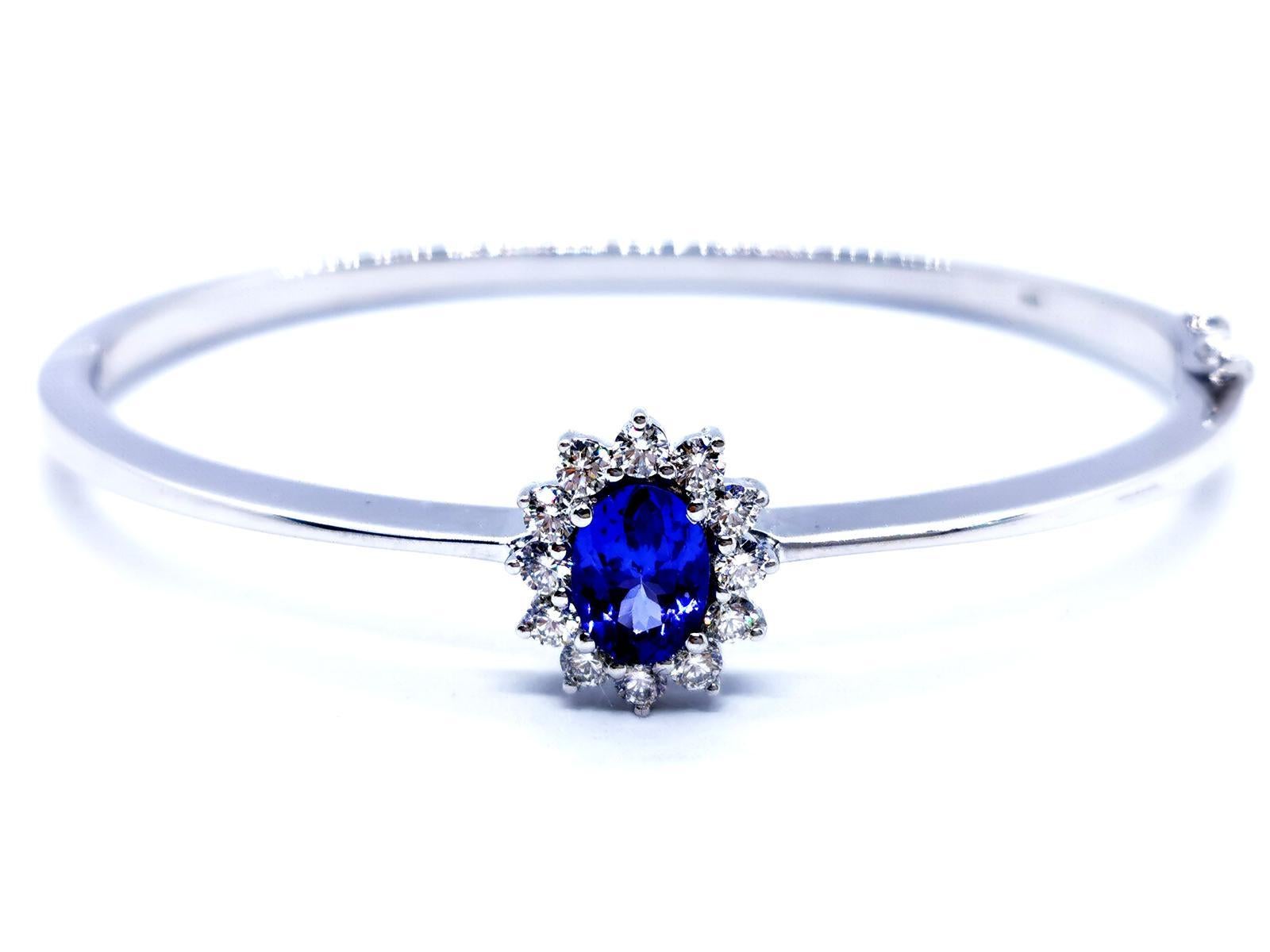 Bangle opening. white gold 750 mils (18 carats). oval. flower pattern. set in the center of a beautiful oval tanzanite dimensions 7.8 mm x 5.8 mm. surrounded by 12 brilliant-cut diamonds. for about 0.42 ct total height: 18 cm. inner diameter: 6 cm x