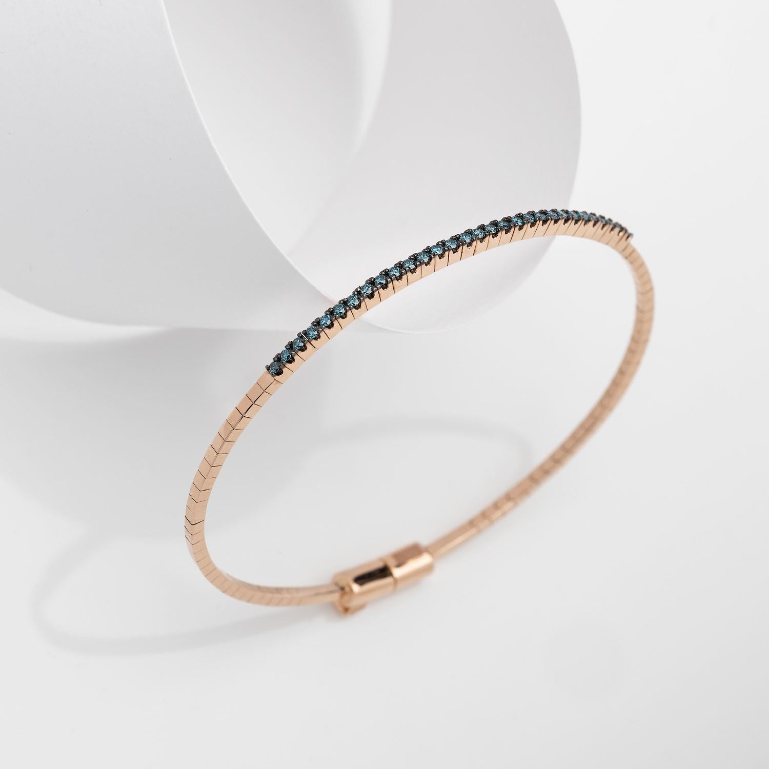 Einzigartiges Armband mit blauen Diamanten im Brillantschliff, handgefertigt in 18 Karat Roségold.
Elegante Streifen aus 18-karätigem Gold schmiegen sich als zarter Schimmer um Ihr Handgelenk. Der blaue Diamant absorbiert und reflektiert das Licht