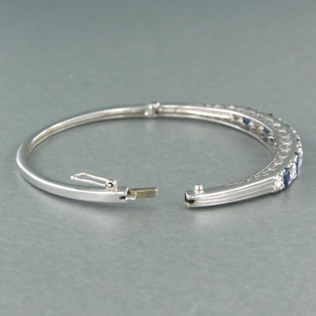 Scharnierarmband aus 14 Karat Weißgold, besetzt mit einem Saphir und einem Diamanten im Brillantschliff - 6,2 cm x 5,5 cm

Ausführliche Beschreibung:

Das Band des Armbands ist 3,7 mm breit und die Oberseite des Armbands ist 5,5 mm breit.

Die