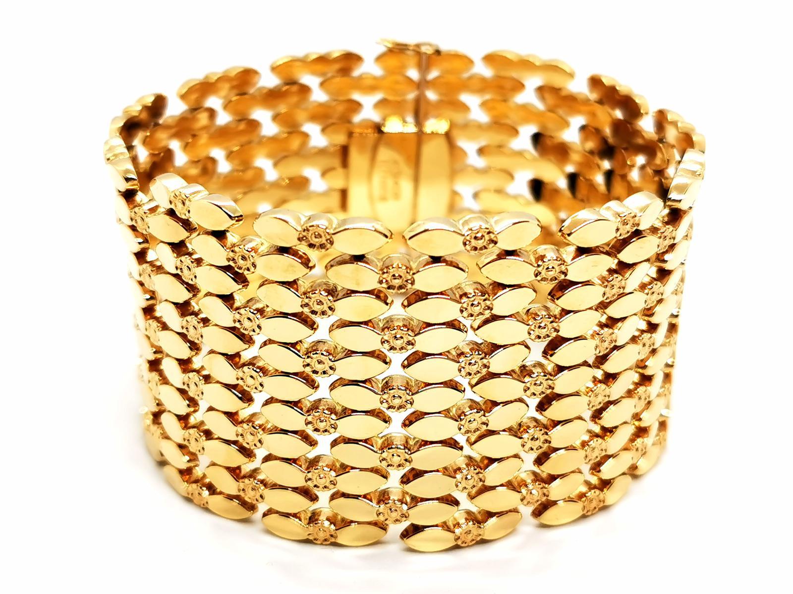 Manschettenarmband. aus Gelbgold 750 Tausendstel (18 Karat). Fancy Mesh. bestehend aus floralen Motiven, die jeweils von Reiskorngliedern getragen werden. Länge: 20,8 cm. Breite: 4 cm. Dicke: 0,28 cm. Verschluss mit zwei Sicherheits-Achteln.
