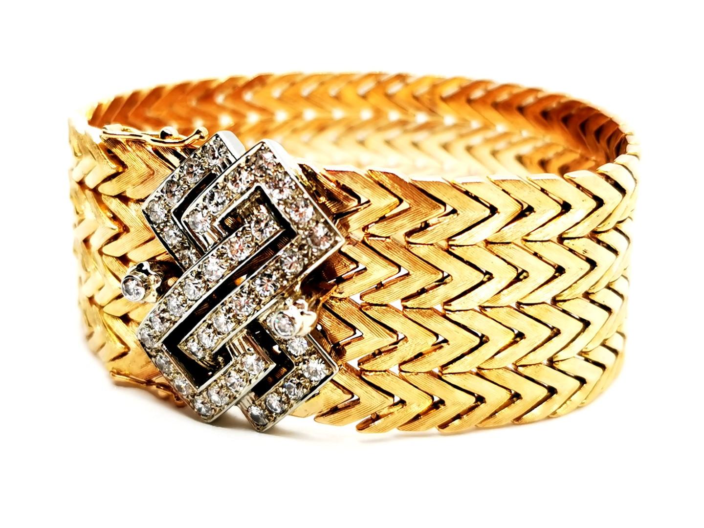 Cuff. golden yellow 750 mils (18 carats). flexible mesh brushed yellow gold. white gold geometric pattern. set with 40 brilliant cut diamonds. about 0.035 ct each. total weight diamonds: about 1.40 carats . length: 18.5 cm. width: 2.55 cm. clasp