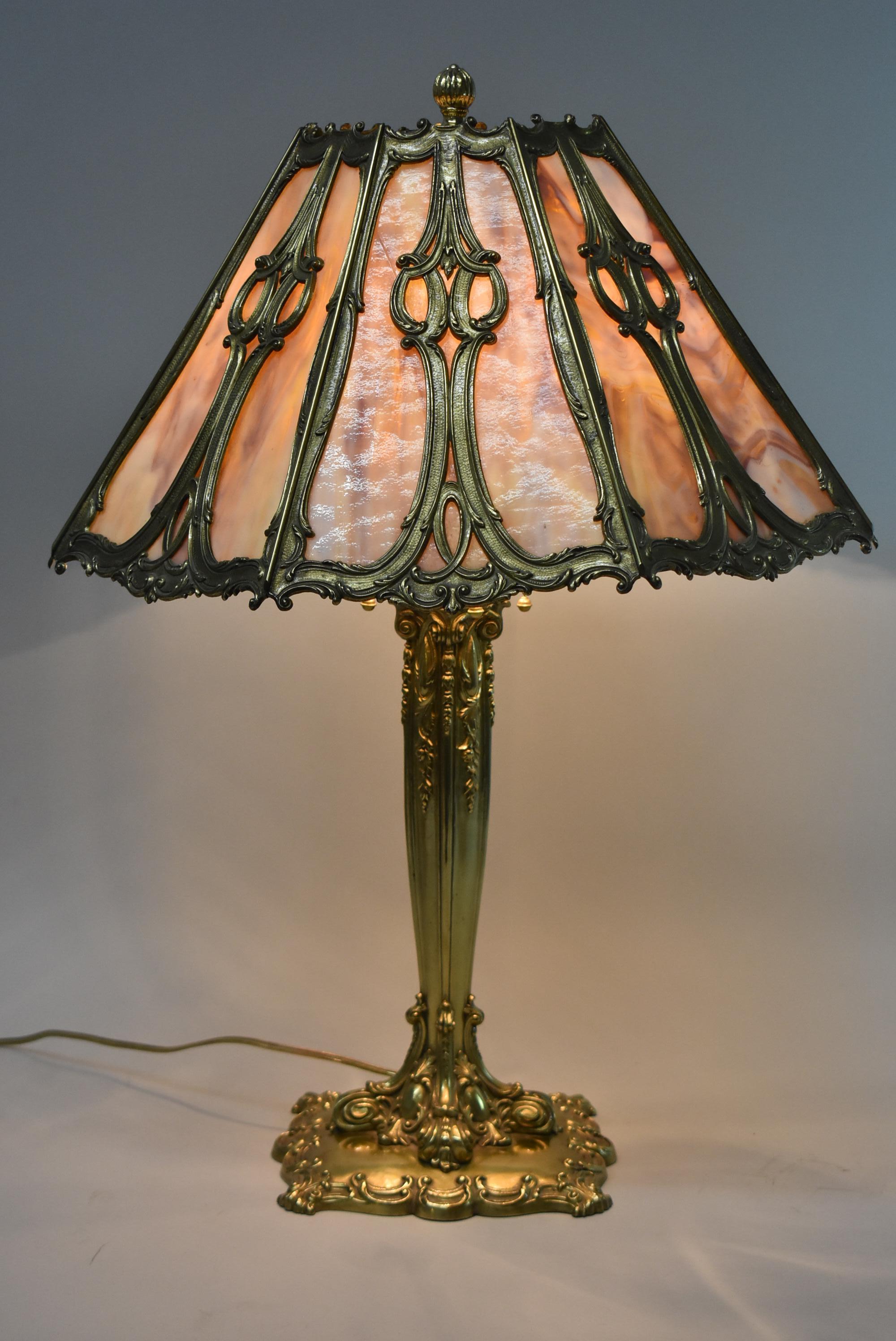 This exceptional lamp by Bradley & Hubbard is dated 1908. The heavy brass base has 4 Bryant sockets with acorn pulls. The base is signed on the underside. There are no breaks in the shade and the piece has been rewired. 18
