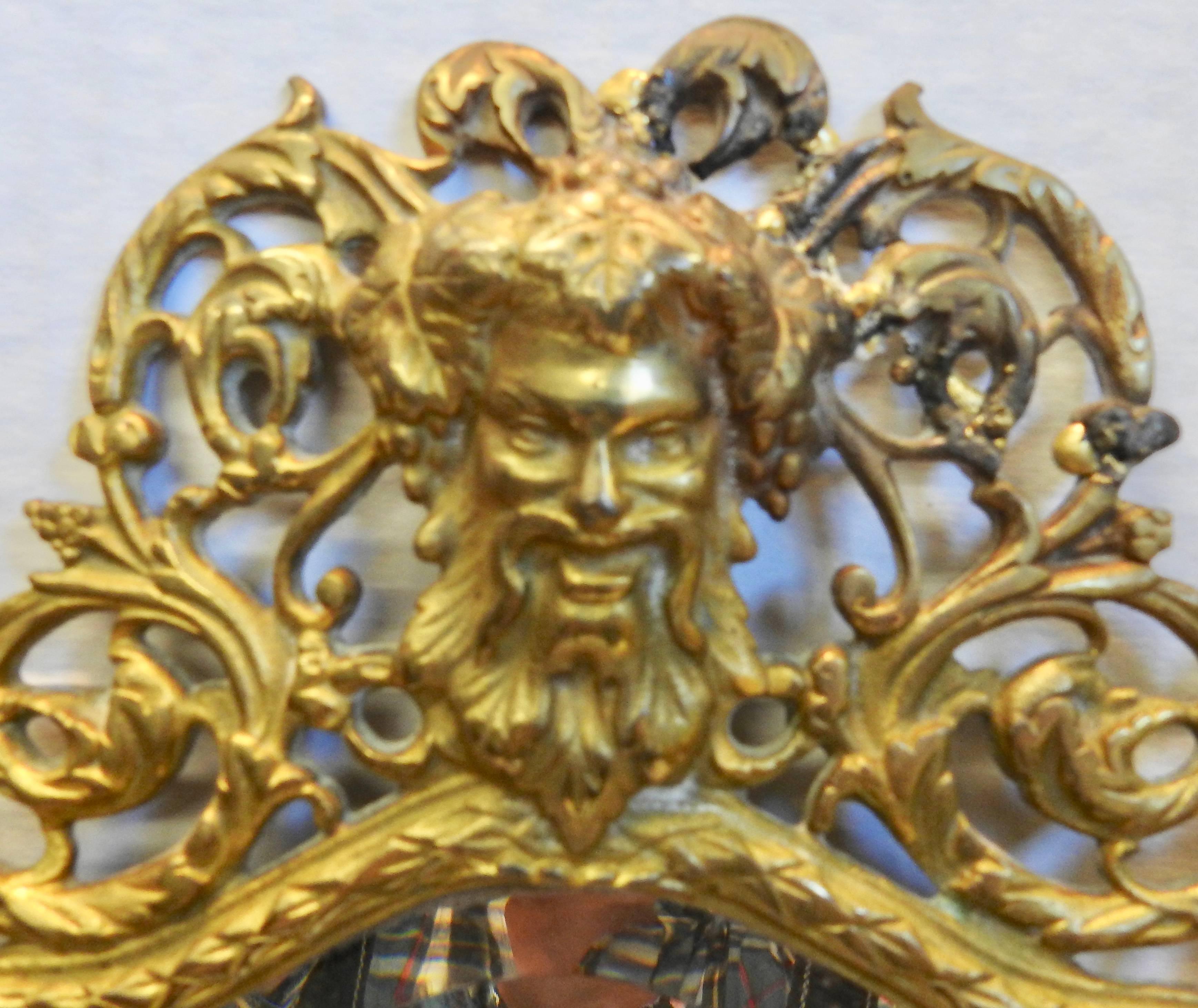 A lovely wall sconce by Bradley and Hubbard with a beveled mirror. There are two candleholders that have the holes drilled to add prisms if you desire. Ornate swirls form the frame for the mirror with a Greek God at the top. The brass is marked on