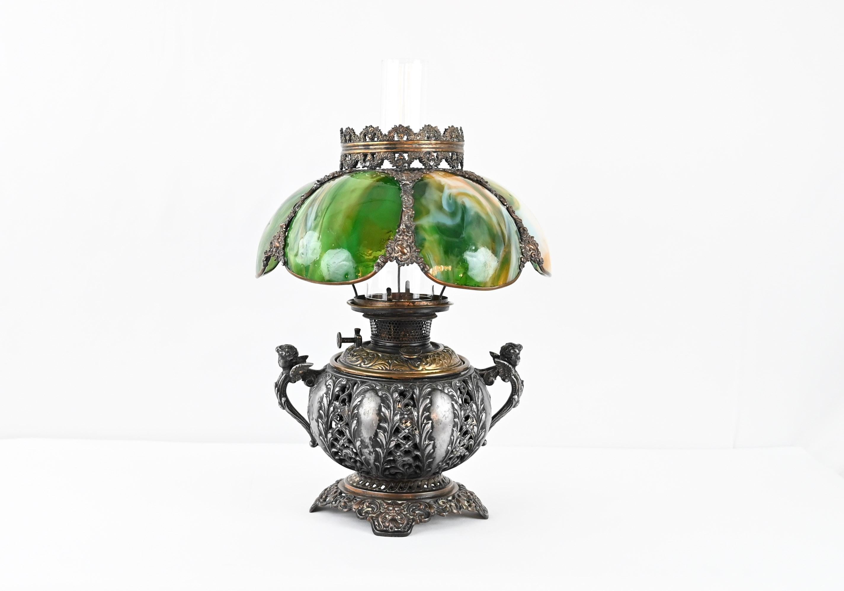 Ancienne lampe à huile Bradley & Hubbard de 1885-1894, B&H gravé sur la base. La lampe est fabriquée en laiton antique et en fonte très ornée, dorée à l'ancienne et avec de magnifiques détails. Abat-jour original en verre peint à la main avec un