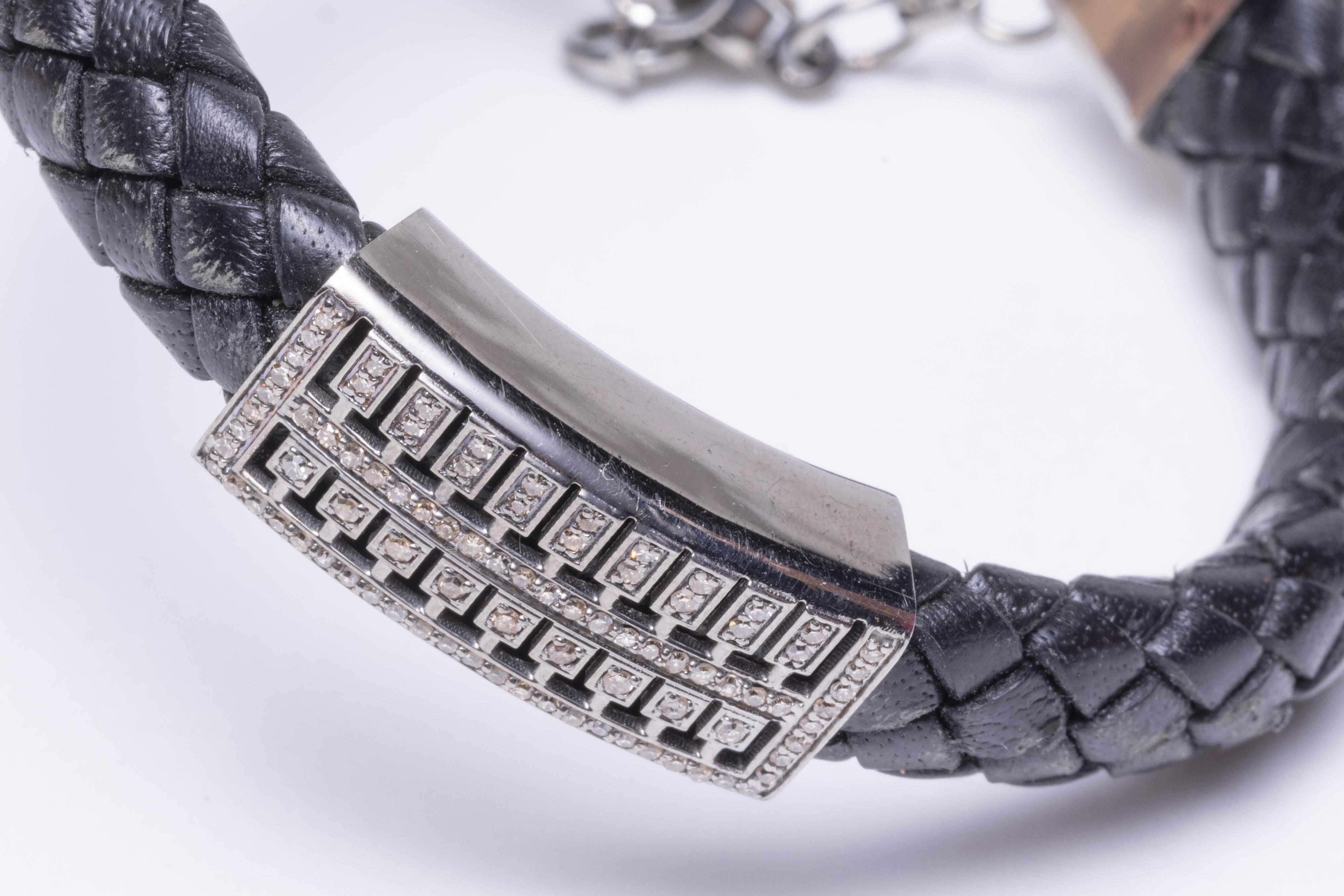 A black braided leather bracelet with round brilliant cut diamonds on sterling silver center piece and end caps.  Adjustable clasp chain ranging from 7.5