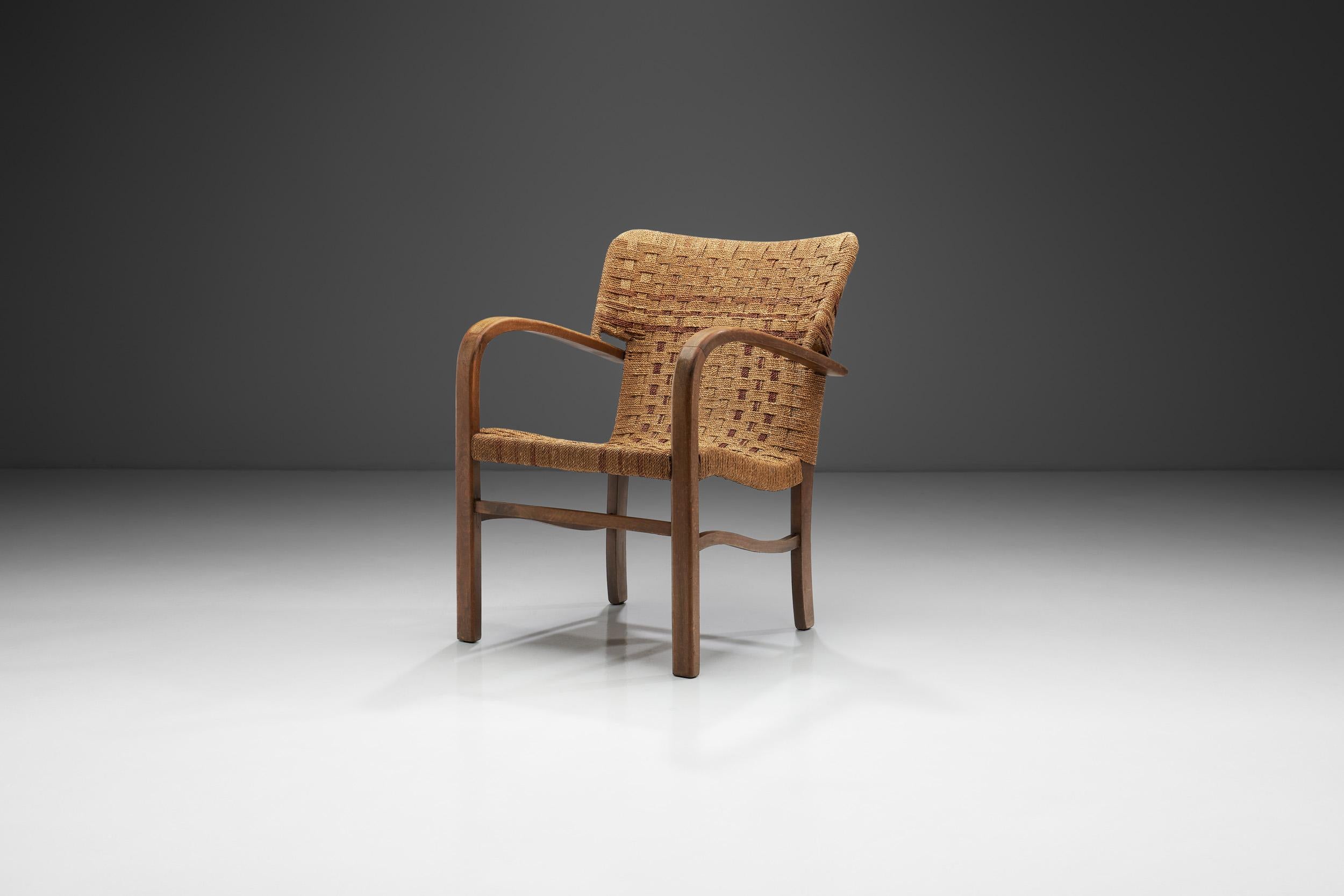 Ce fauteuil, rappelant le Bauhaus, est fait de bois et de corde tressée, et rappelle les designs iconiques du début du 20e siècle. Les modèles de meubles d'Erich Dieckmann se caractérisent souvent par des bois durs de qualité, des tapis de canne et