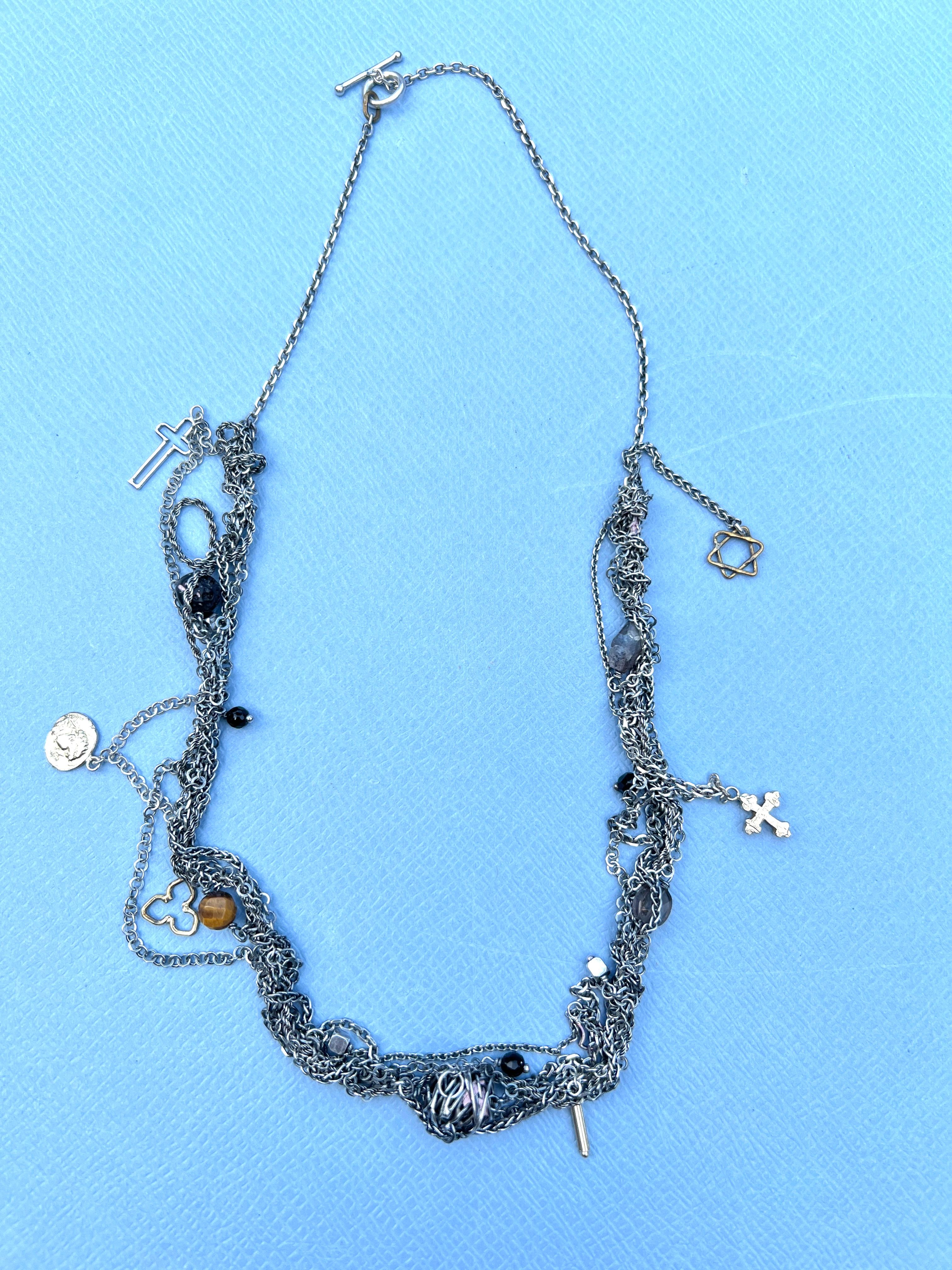 Collana a catena d'argento intrecciata Spinello Occhio di tigre Labradorite Croce di David

Lunghezza: 19 pollici

Questa collana a catena d'argento intrecciata dal design intricato è ornata da una ricca serie di ciondoli e gemme simboliche, ognuna