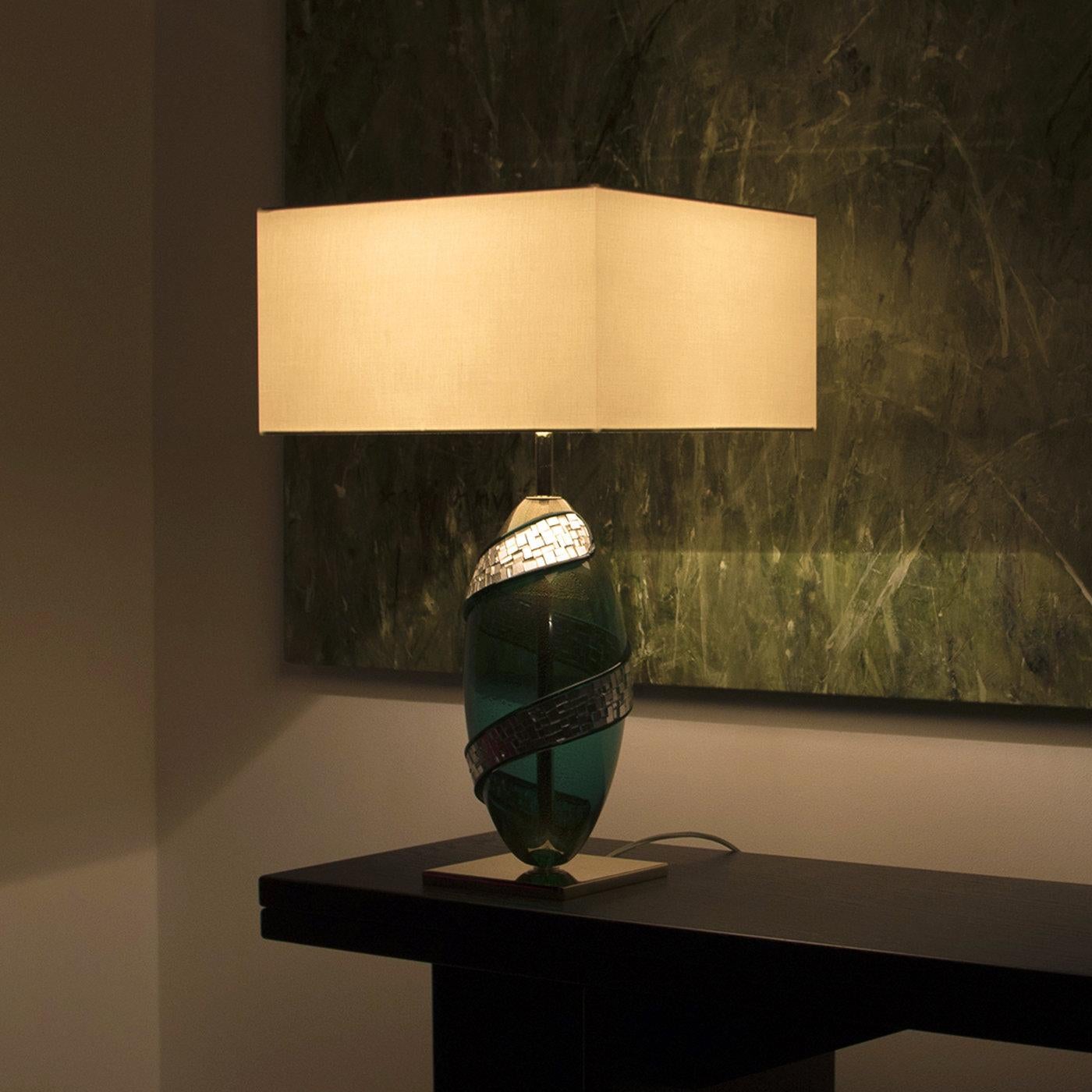 Part of the Light Collection, this stylishly original Green Brama Lamp is a craving for uniqueness. The Murano emerald green blown glass and subtle gold support the delightful white gold mosaic between two emerald green glass threads. The structure